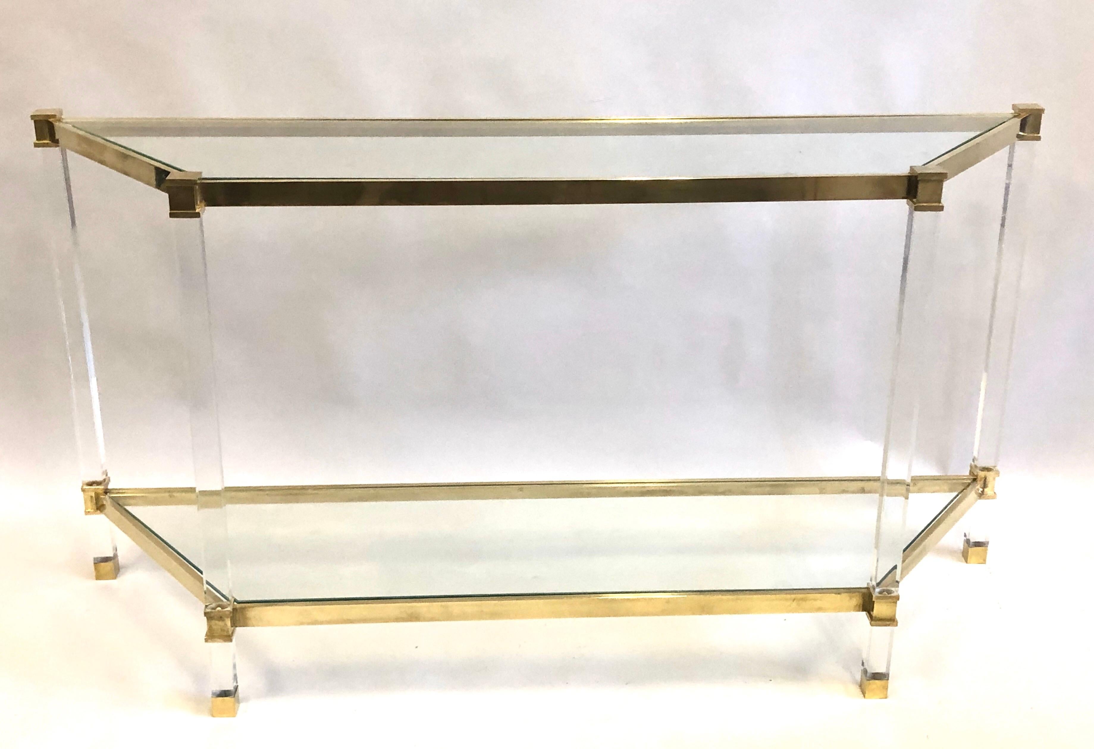 Une élégante et intemporelle console ou table de canapé à deux niveaux en Lucite, laiton et verre de forme trapézoïdale, conçue par Pierre Vandel et utilisée par la boutique Hermès de Florence, en Italie.  La pièce exprime l'essence du modernisme