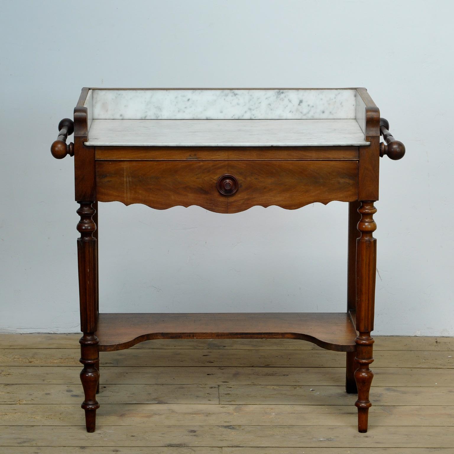 Antique French oak dressing table with marble top with a drawer underneath. A rod on the sides to hang a towel.
The table was made around 1920. 