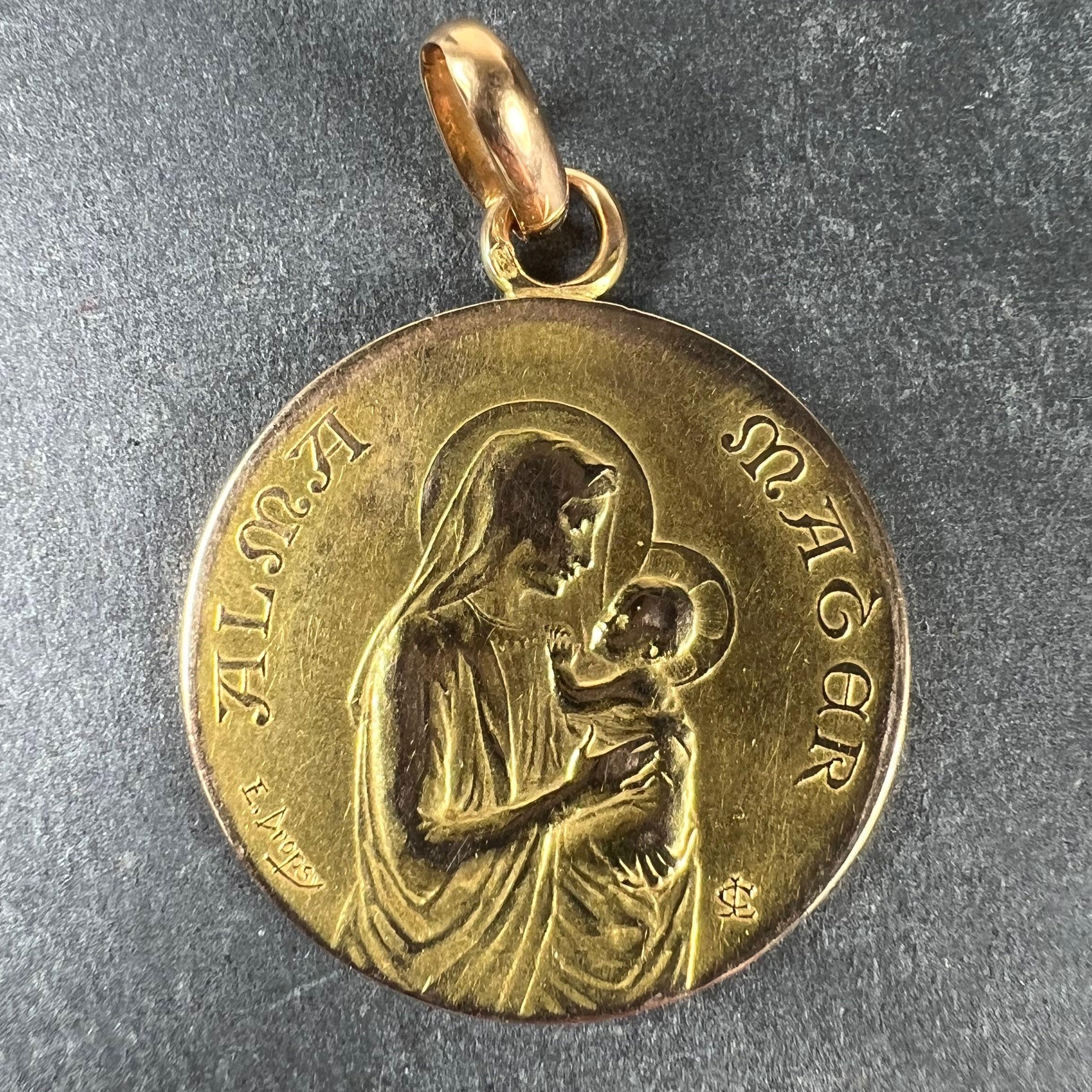 A French 18 karat (18K) yellow gold charm pendant designed as a round medal with a relief of the Madonna and Child with halos, with the Latin motto 'ALMA MATER' (Nourishing Mother) above. The reverse with a frame of entwined liles surmounted by a