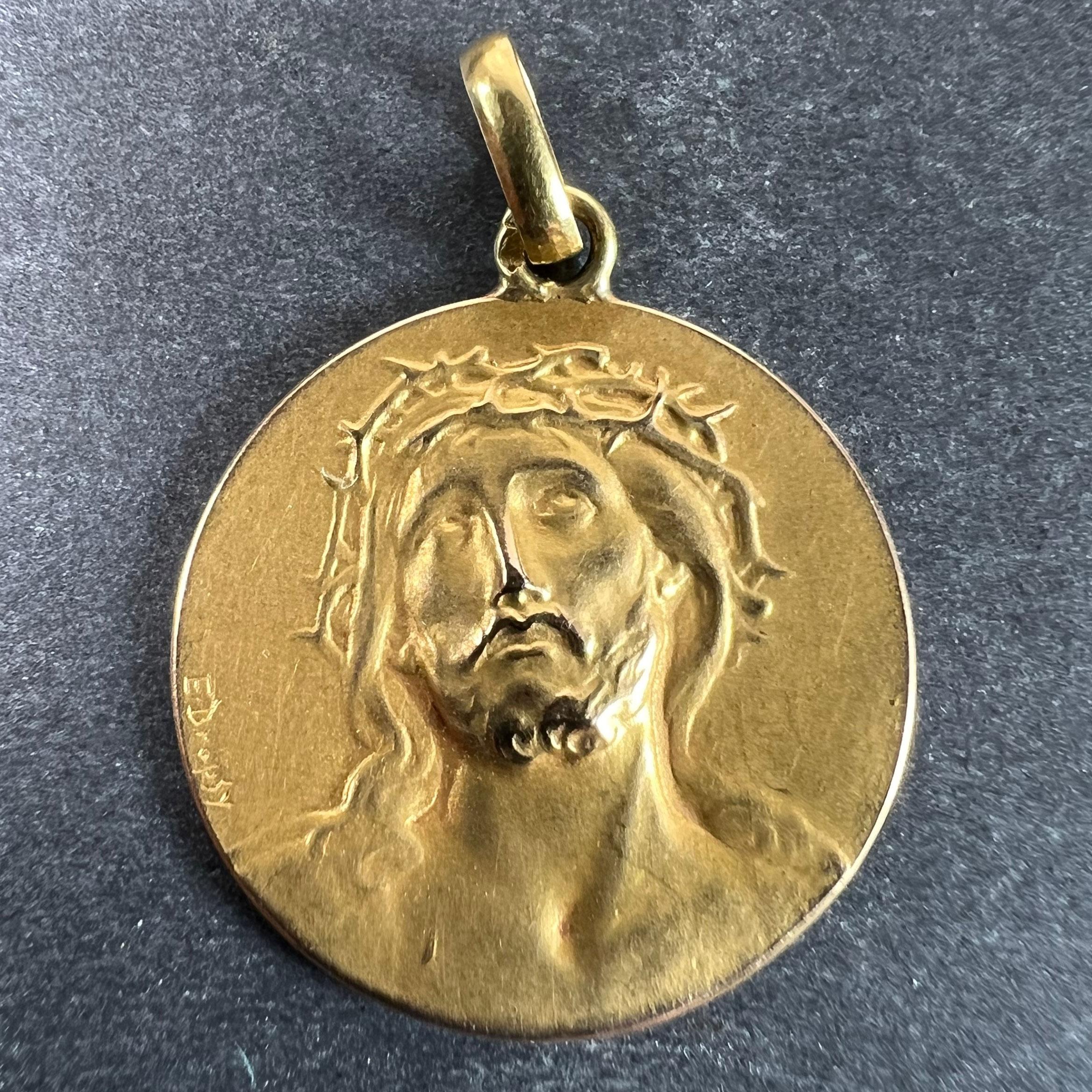 A French 18 karat (18K) yellow gold charm pendant designed as a round medal depicting Christ wearing the Crown of Thorns. The reverse depicts an olive branch symbolising peace. Signed E. Dropsy, stamped with the eagle’s head for 18 karat gold and
