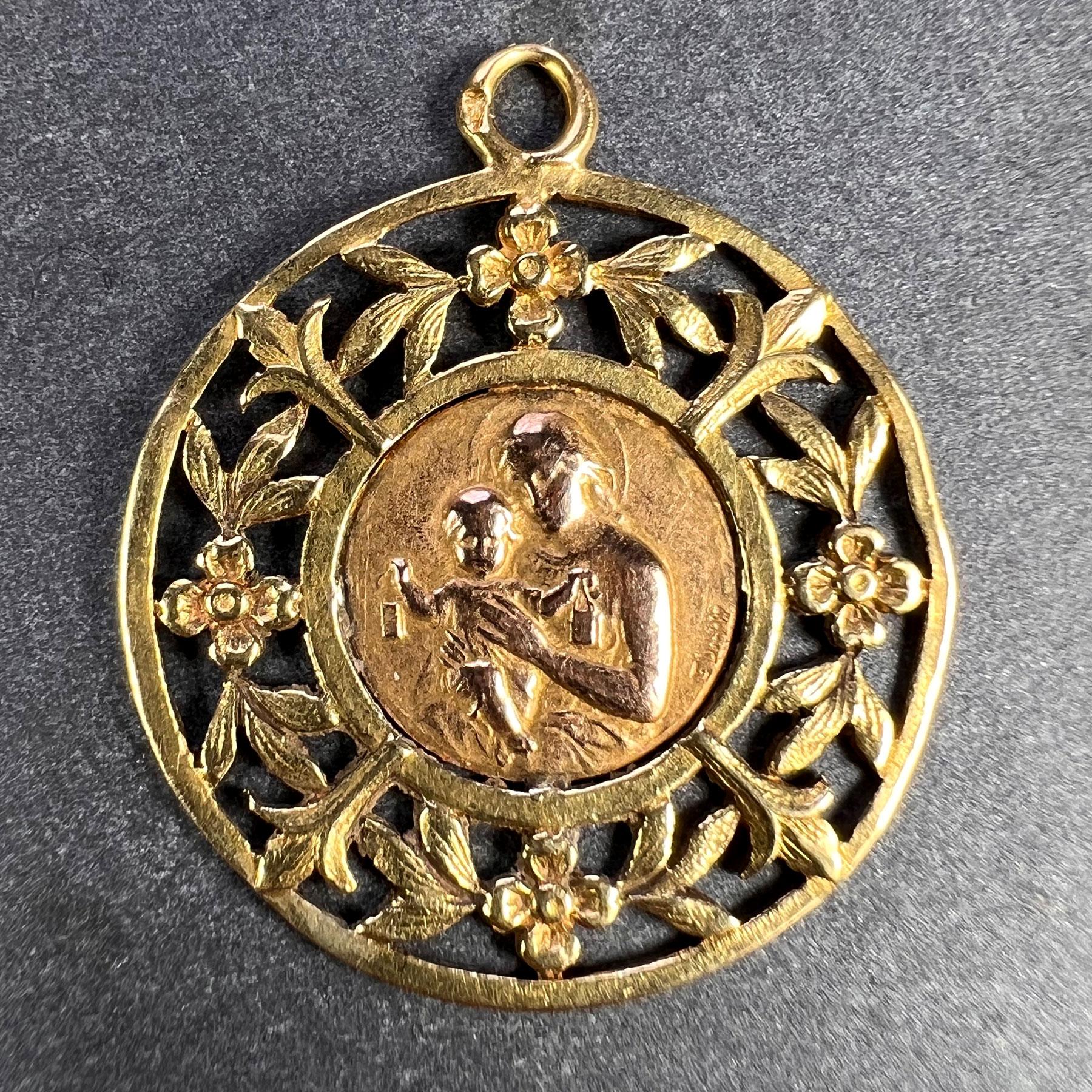 A French 18 karat (18K) yellow and rose gold charm pendant designed as a rose gold medal depicting the Madonna and Child signed by E. Dropsy, surrounded by a yellow gold floral frame. The reverse is engraved with a monogram of YP. Stamped with the
