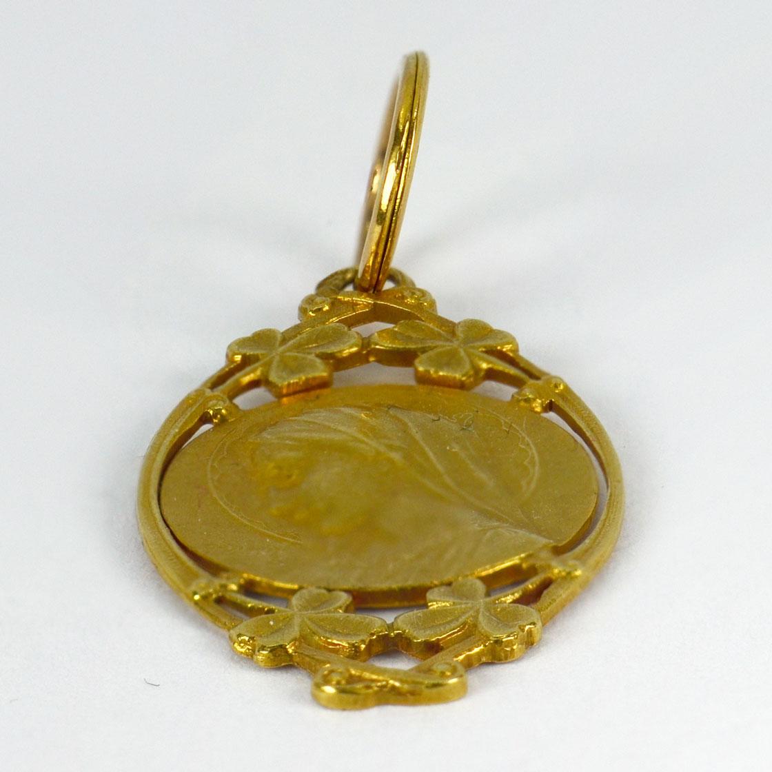 A French 18 karat (18K) yellow gold charm pendant designed as the Virgin Mary surrounded by clover leaves, with a monogram for GS and the date ‘Juin 39’ to the reverse. Signed R. Dropsy. Stamped with the eagle’s head for French manufacture and 18