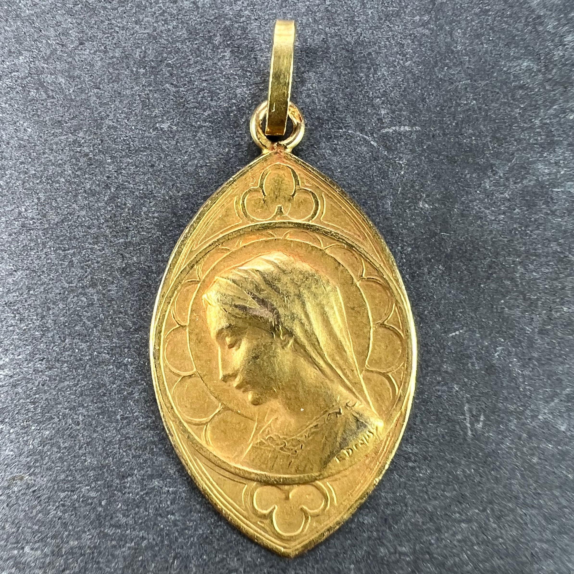 A French 18 karat (18K) yellow gold navette shaped charm pendant or medal designed by Dropsy depicting the Virgin Mary within a central circle with a gothic arch window surround. Stamped with the eagle's head for French manufacture, an unknown
