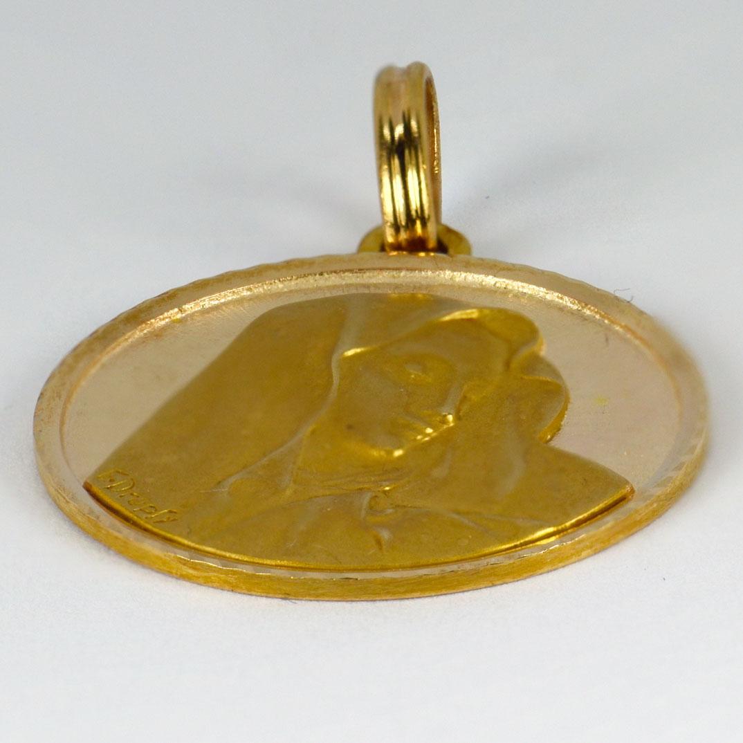 An 18 karat (18K) yellow gold pendant designed as a round medal depicting the Virgin Mary. Signed E. Dropsy. Stamped with the eagle’s head for French manufacture and 18 karat gold, with unknown maker’s mark.

Dimensions: 2.8 x 2.4 x 0.2 cm (not