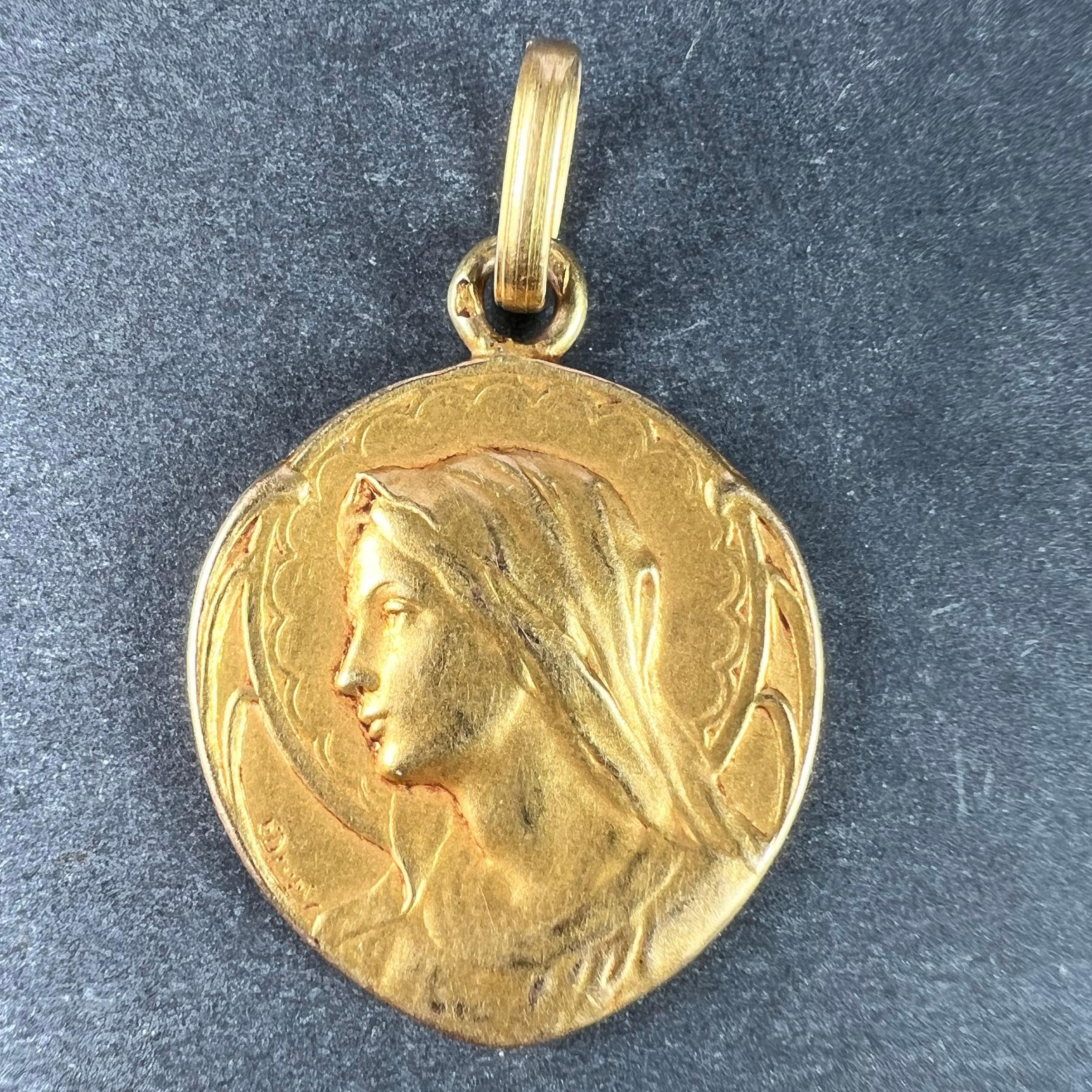 An 18 karat (18K) yellow gold pendant designed as a shield-shaped medal depicting the Virgin Mary with a halo and an Art Nouveau surround. Signed E. Dropsy. The reverse depicts a radiating crown of stars with long stemmed roses to either side