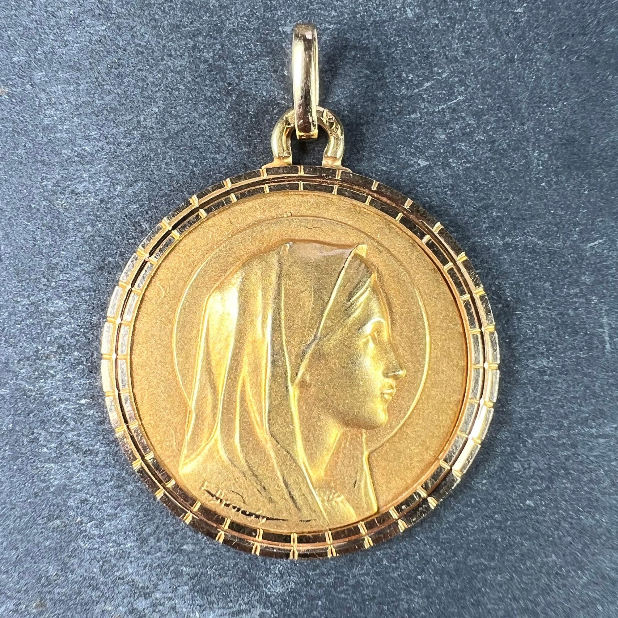 An 18 karat (18K) yellow gold pendant designed as a round medal depicting the Virgin Mary with a halo and a polished and ridged surround. Signed E. Dropsy. The reverse depicts a person praying at the feet of the Virgin Mary. Stamped with the eagle’s