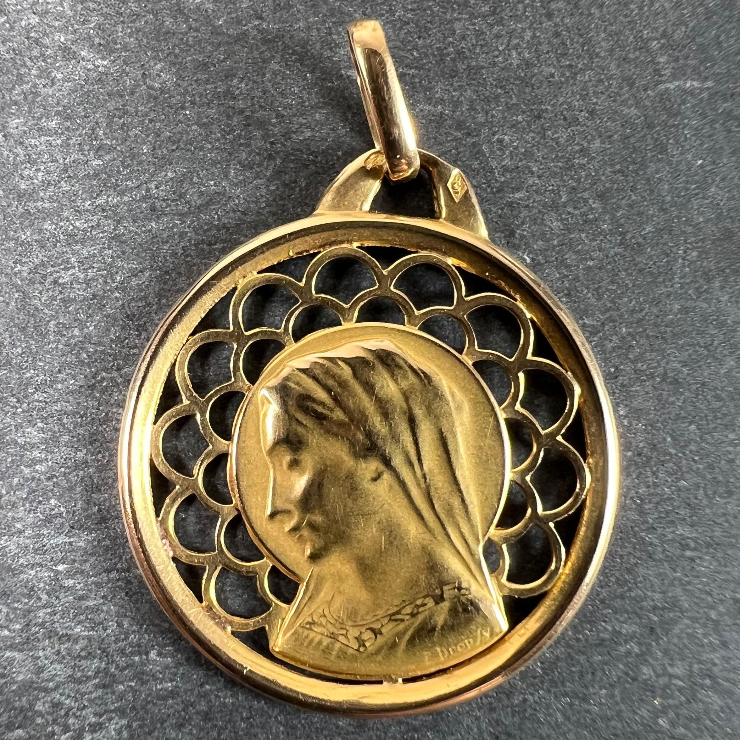 A French 18 karat (18K) yellow gold charm pendant designed as a medal depicting the Virgin Mary in a halo within a pierced gothic arch sunburst. Signed E. Dropsy, stamped with the eagle mark for 18 karat gold and French manufacture with an unknown