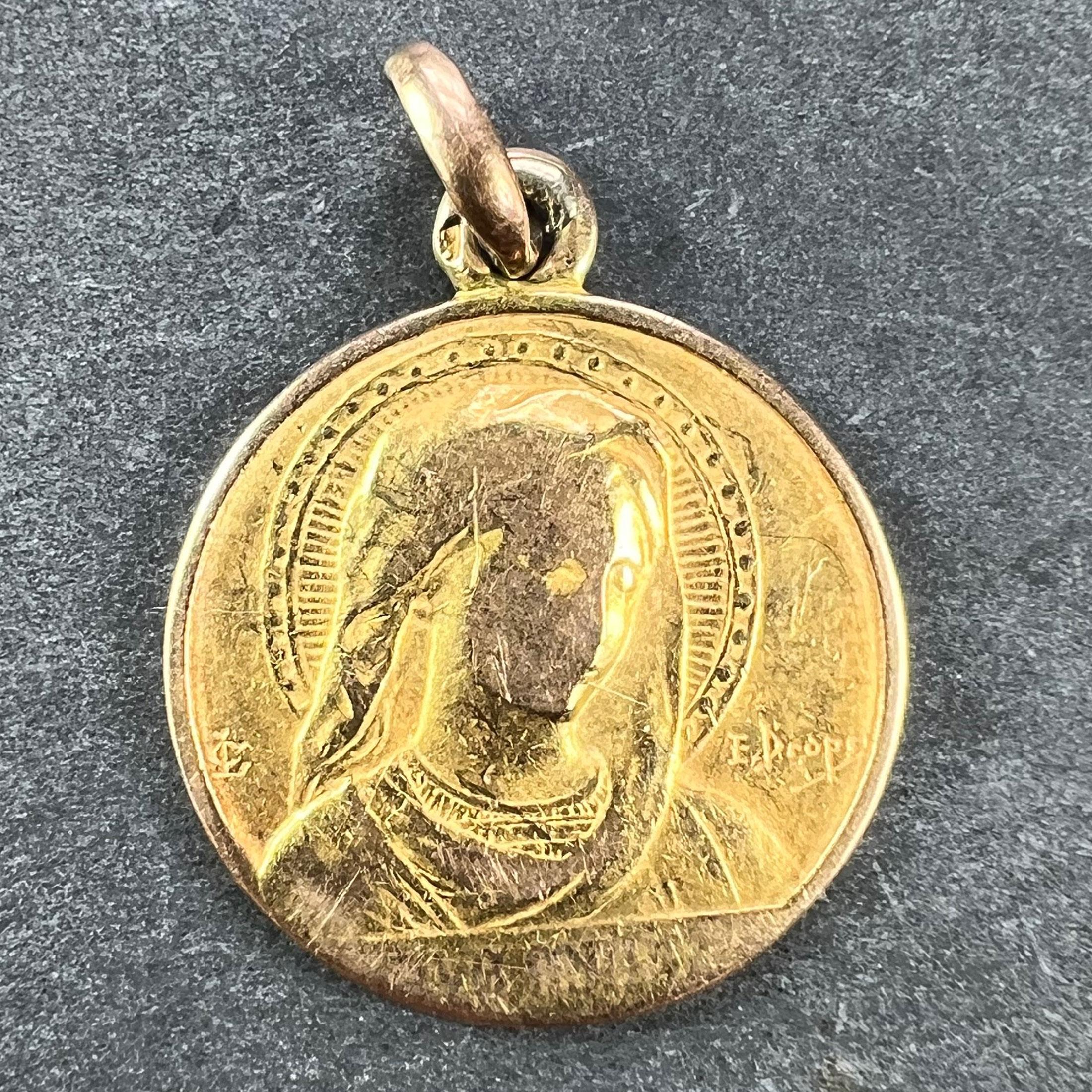 An 18 karat (18K) yellow gold charm pendant designed as a medal depicting the Virgin Mary in a halo, over the words Ave Maria. Signed E. Dropsy, stamped with the eagle mark for 18 karat gold and French manufacture with an unknown maker's mark. The