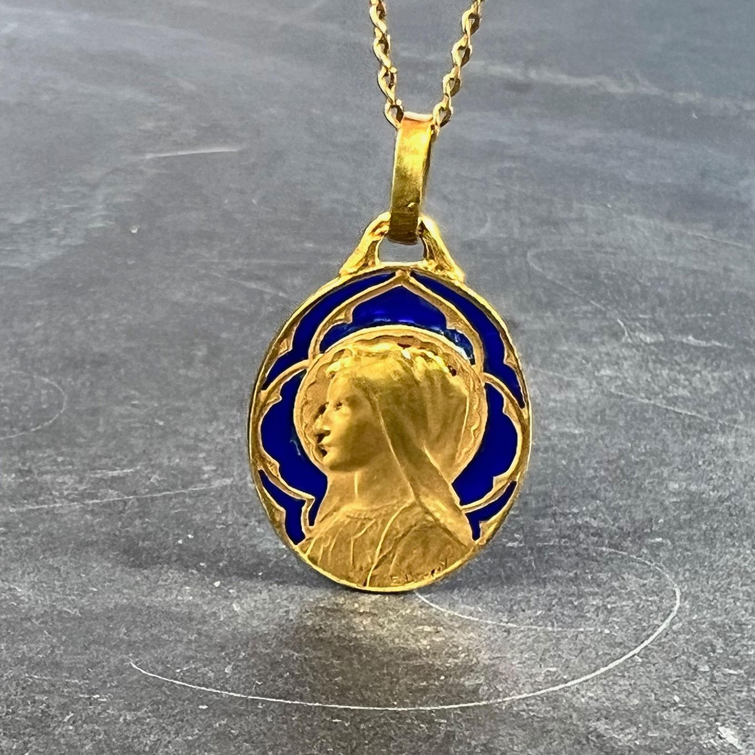 A French 18 karat (18K) yellow gold charm pendant designed as an oval medal depicting the Virgin Mary with plique a jour blue enamel surround. Signed E Dropsy, stamped with the eagle’s head for 18 karat gold and French manufacture, and a partial