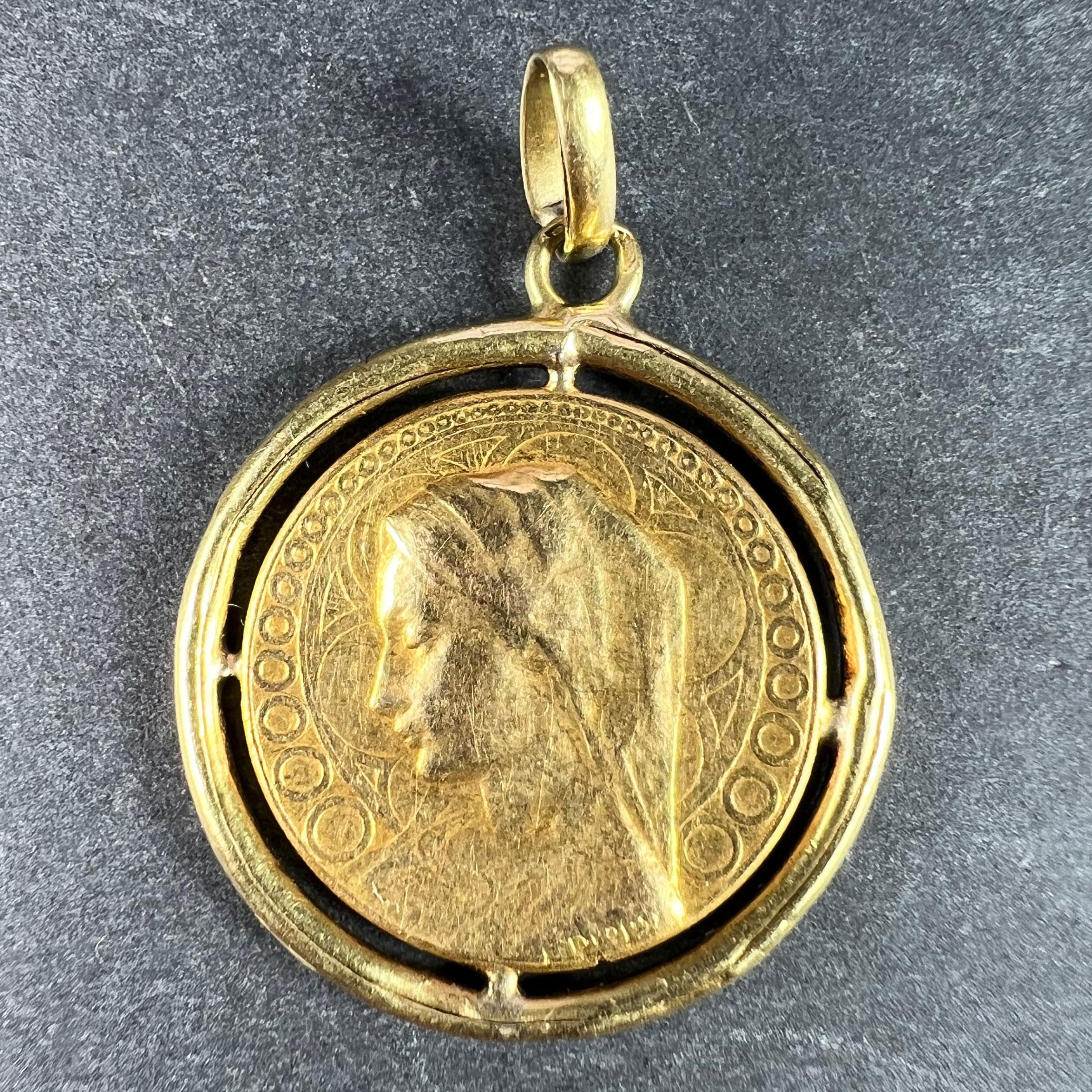 A French 18 karat (18K) yellow gold charm pendant designed as a medal depicting the Virgin Mary within a border of circles signed by E. Dropsy, surrounded by a yellow frame. The reverse features a sheaf of lilies and the phrase 'Virgo Gloriosa'