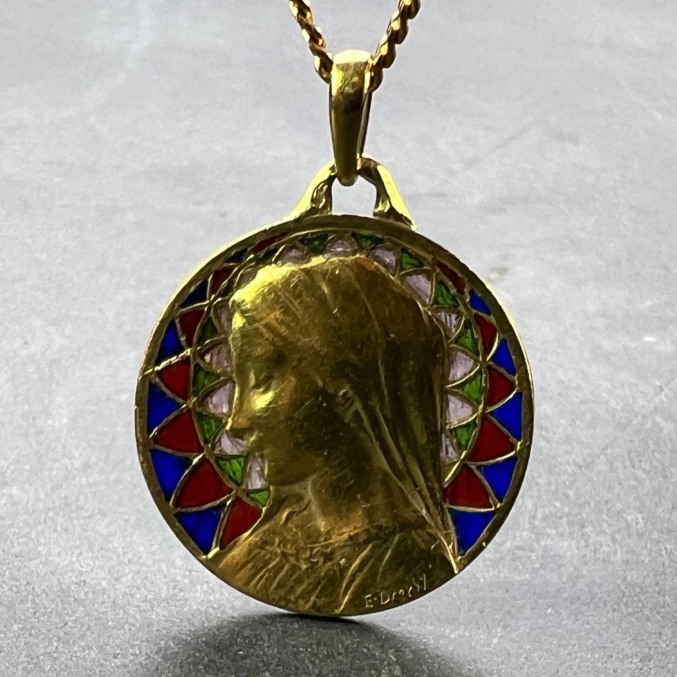 A French 18 karat (18K) yellow gold charm pendant designed as a round medal depicting the Virgin Mary with plique a jour red, blue, green and colourless enamel surround. Signed E. Dropsy, stamped with the eagle’s head for 18 karat gold and French