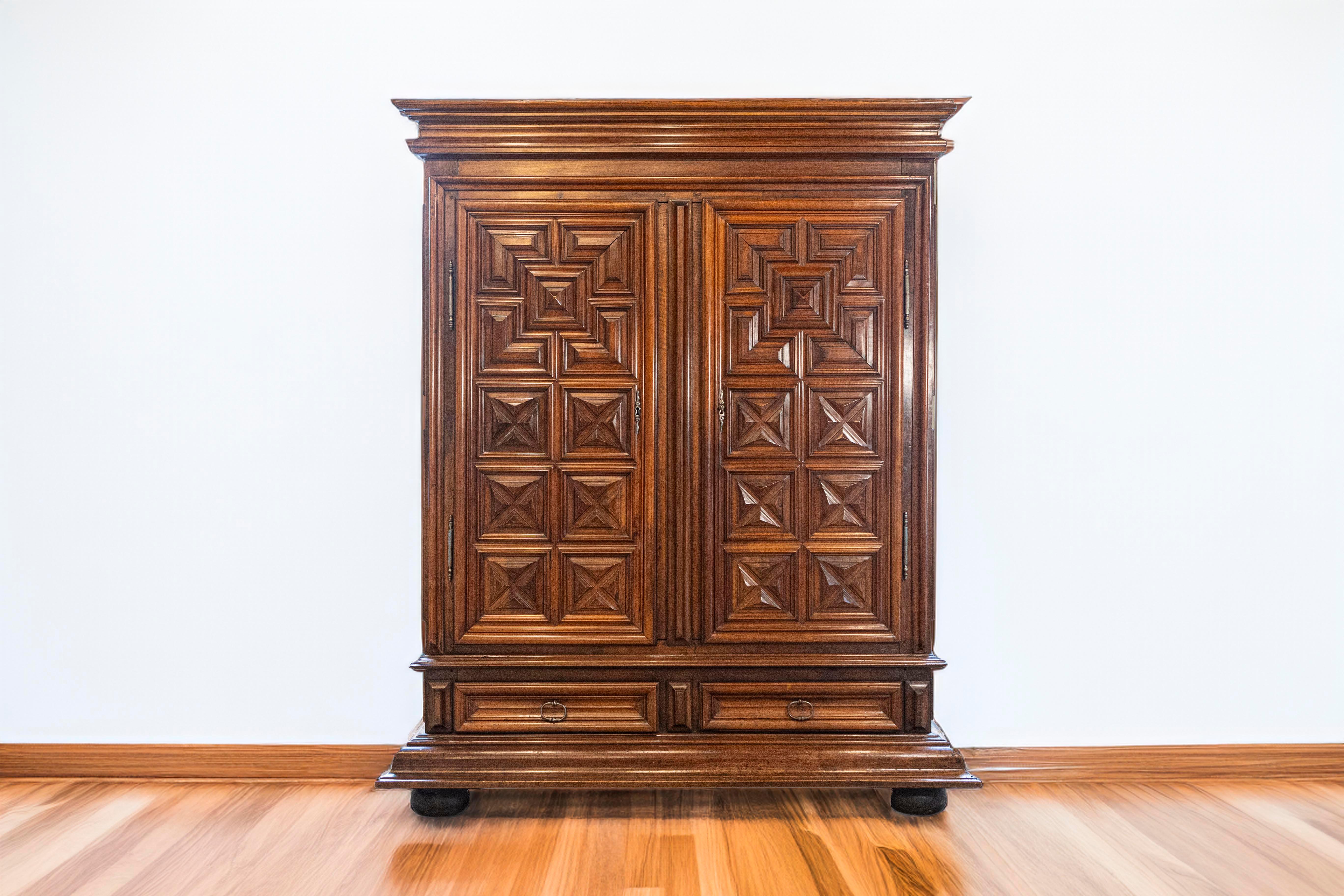 A French early 17th century large scale period Louis XIII walnut armoire with two doors over two drawers, geometric décor and original hardware. With this piece, we are in the middle of the reign of King Louis XIII (the original creator of
