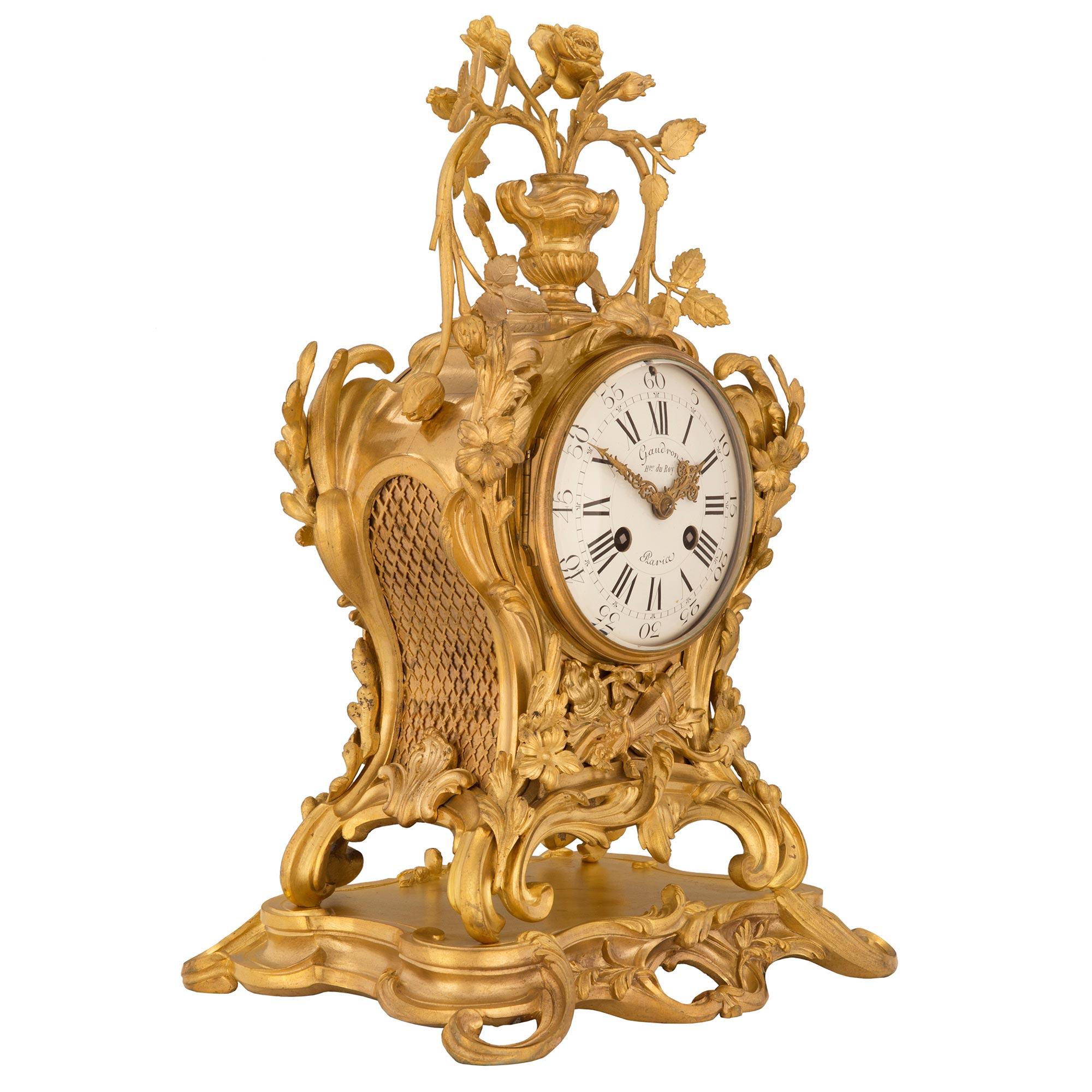 Superbe pendule en bronze doré d'époque Louis XV du début du XVIIIe siècle, signée Gaudron du Roy, Paris. La pendule repose sur une base en bronze doré avec des mouvements à volutes luxuriantes. Sous le cadran et au centre de l'horloge se trouve une