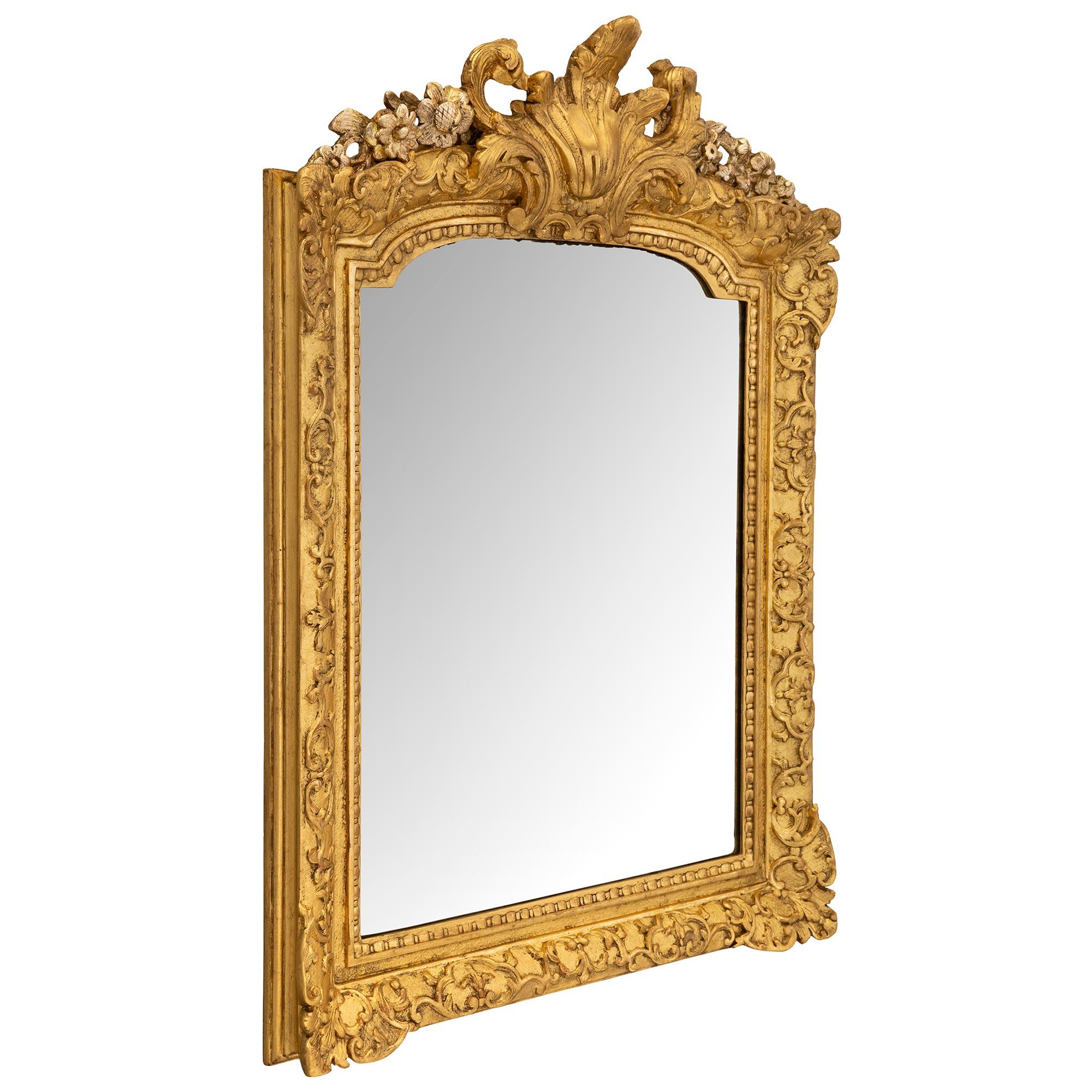 A stunning and most charming French early 18th century Régence period giltwood and mecca mirror. The mirror retains its original mirror plate set within a fine mottled, reeded, and beaded frame. Beautiful and extremely decorative interlocking