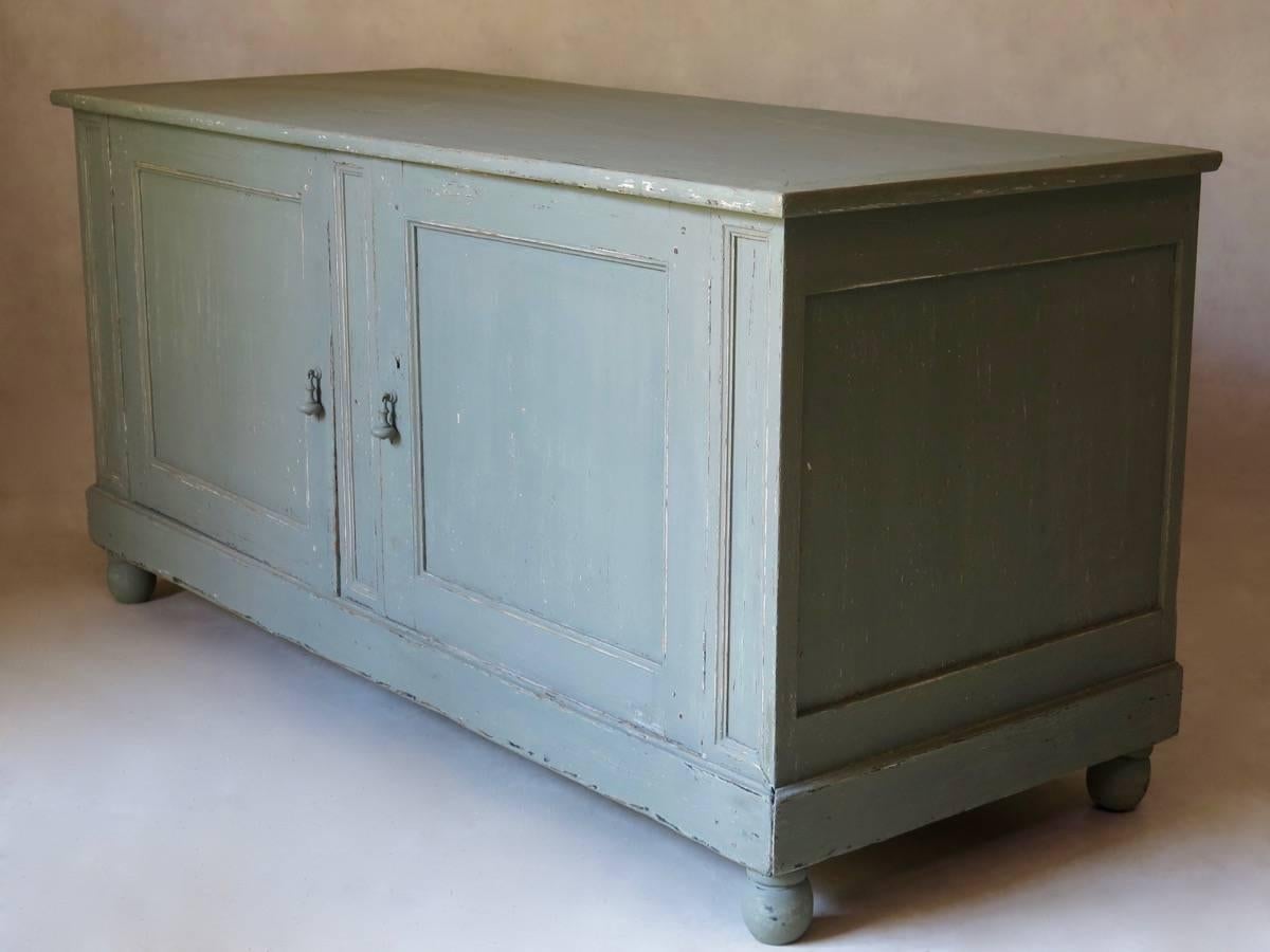Elegant and capacious, rustic style, grey/blue painted pinewood enfilade, fitted with shelves, and raised on ovoid ball feet. Pompon-like hardware (door pulls).