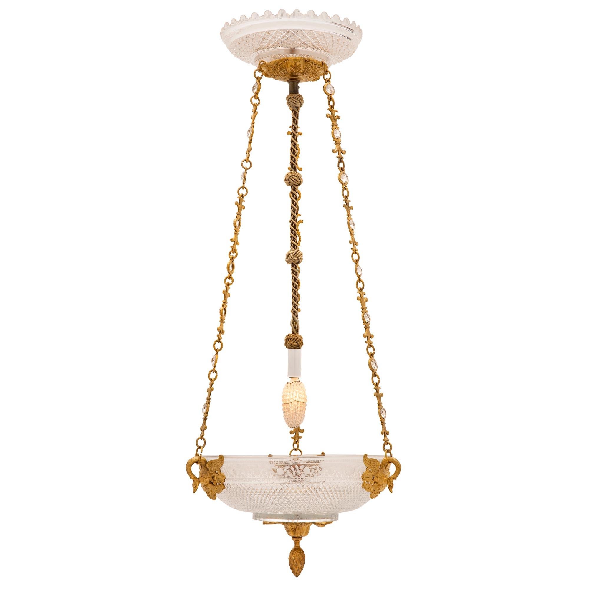 A most elegant and unique French early 19th century 1st Empire period Baccarat crystal and ormolu chandelier. The chandelier is centered by a charming and richly chased bottom ormolu acorn finial surrounded by lovely foliate designs. The most