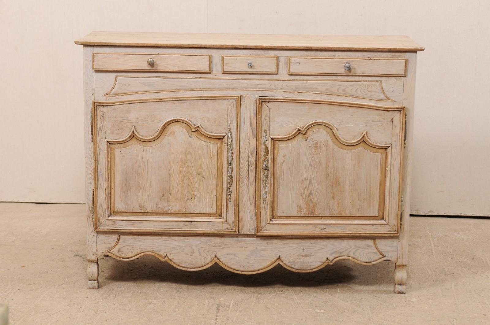 A French carved wood buffet cabinet from the early 19th century. This antique cabinet from France features a rectangular-shaped top with rounded front corners, atop an upper row of three thinly profiled drawers, which are seated above a pair of