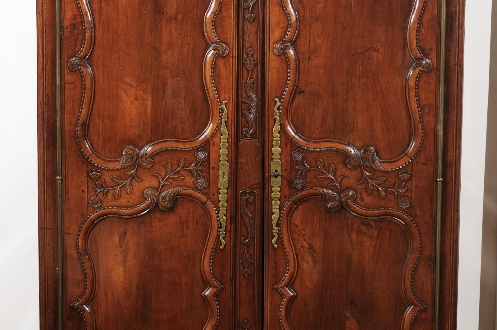 A French early 19th century Bretonne cherry armoire from Rennes with double bonnet top and carved décor. Born in the capital of Brittany during the first quarter of the 19th century, this cherry armoire features a double bonnet top adorned with
