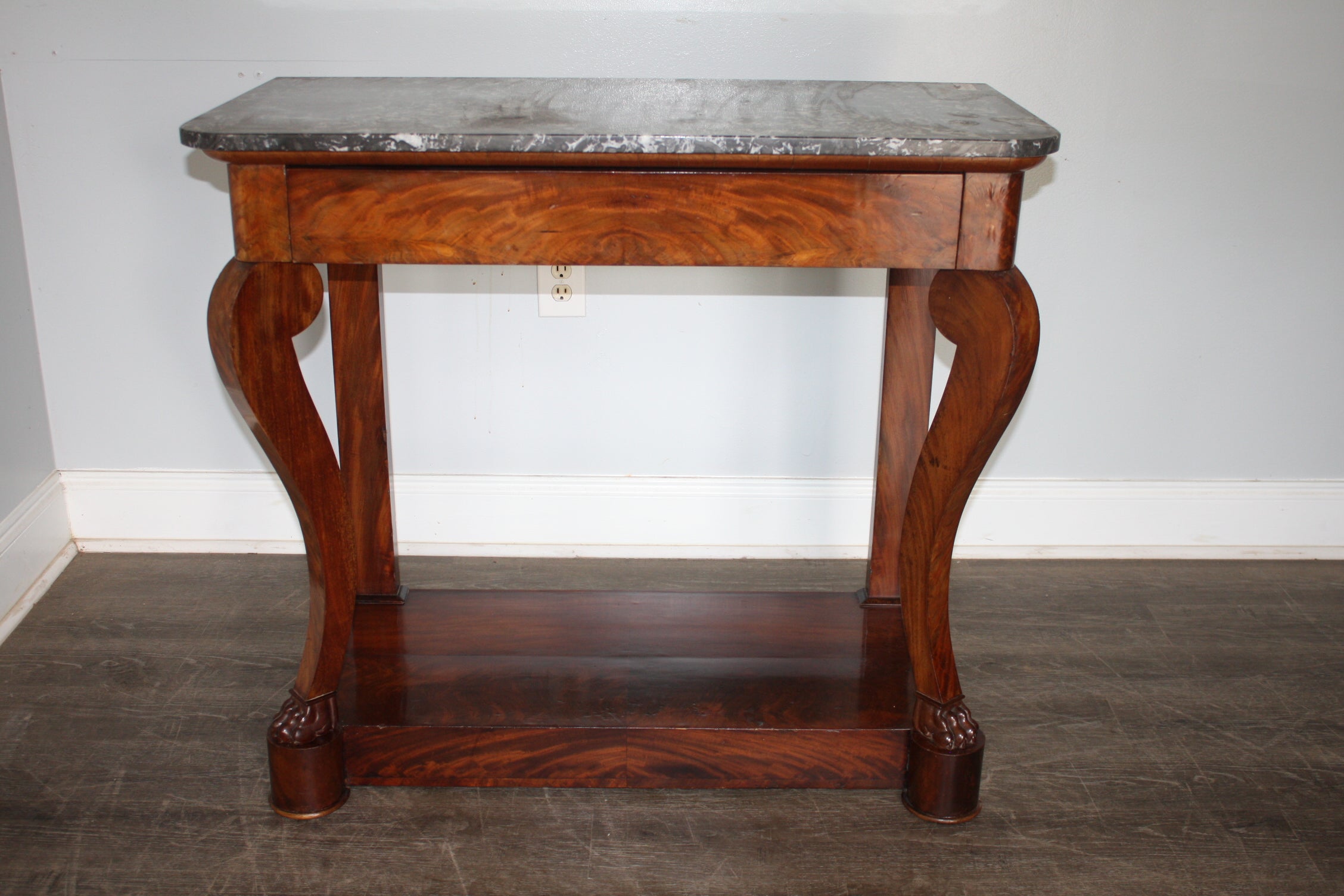 This wonderful console is made of blond flamed mahogany with a Sainte-Anne marble top. It has a drawer hidden on the belt.