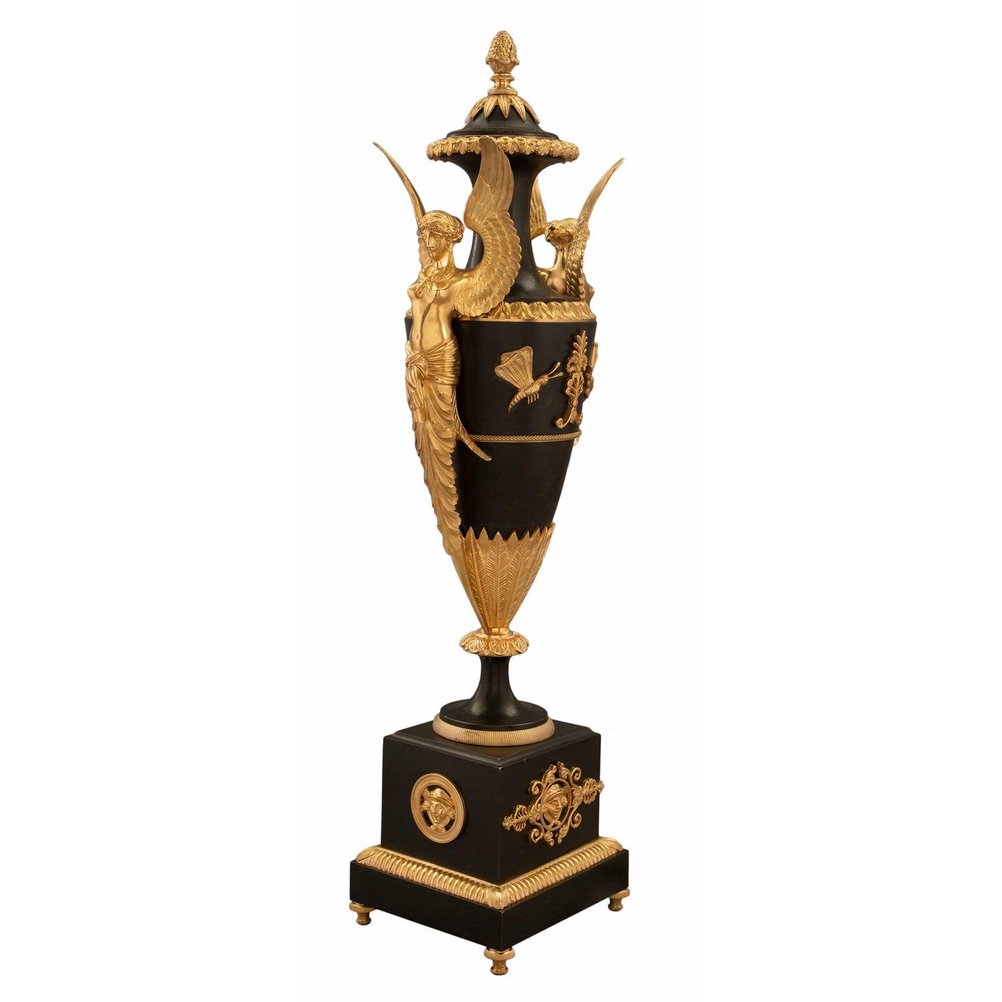 Une paire sensationnelle d'urnes françaises du début du XIXe siècle, de style Premier Empire, en bronze patiné et bronze doré, attribuée à Claude Galle. Chaque urne est surélevée par une base carrée en bronze patiné, dotée d'élégants pieds en forme