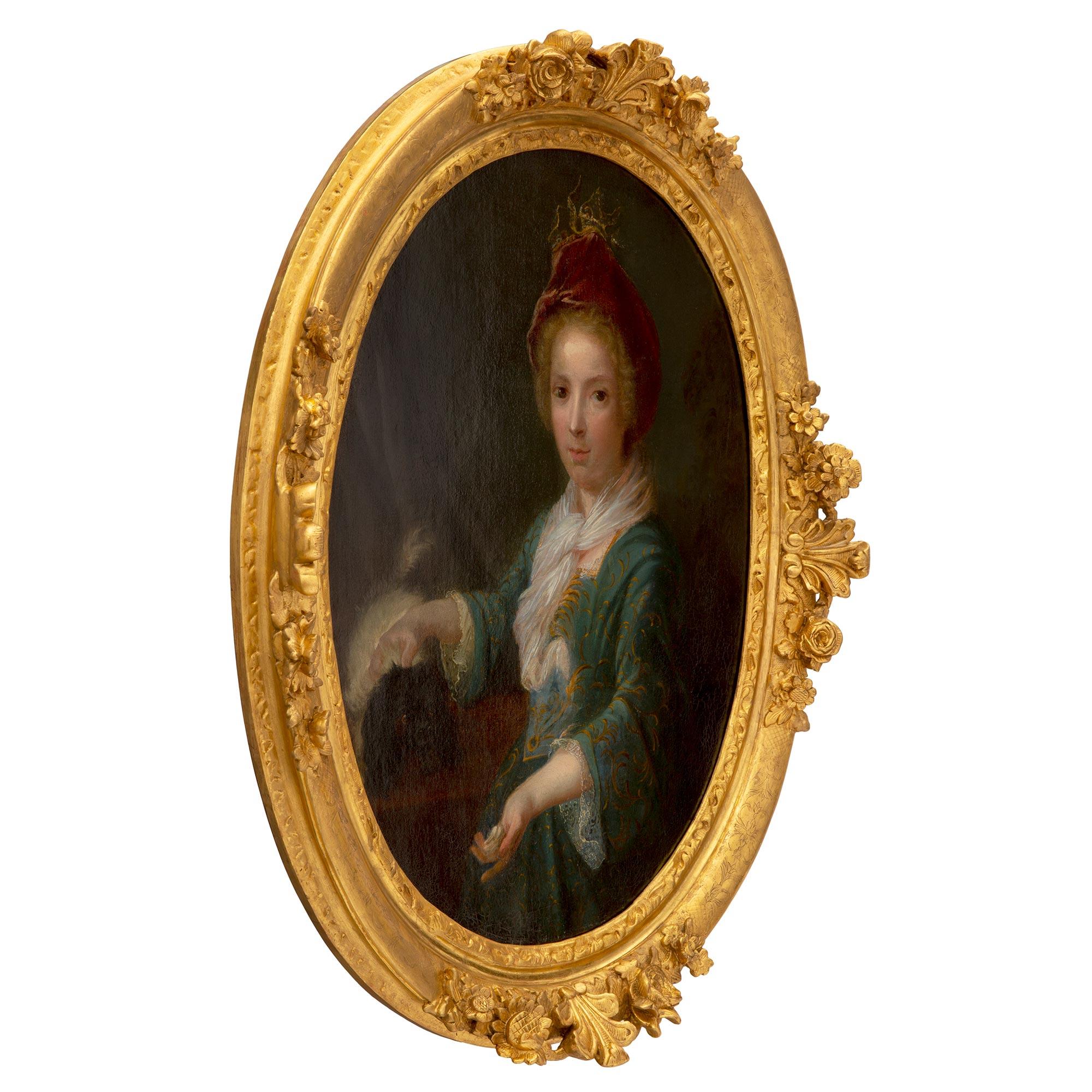 A most elegant French early 19th century giltwood and oil on canvas portrait of a young girl. The oval painting retains its original frame decorated with four richly carved reserves with a central palmette flanked by beautiful blossoming flowers.