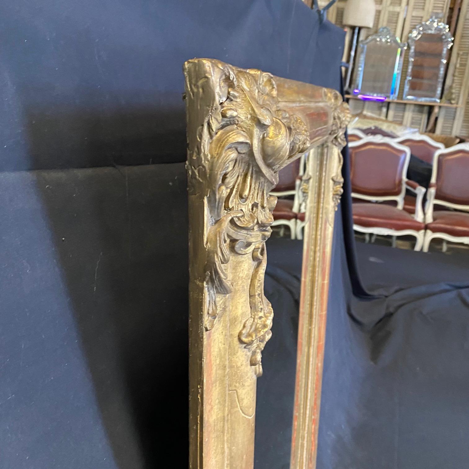 Elegant French antique gold mirror from Paris, from the atelier of Alex dre Rigalt at the Grand Place de St. Ouen, with maker's mark on the original back. There are beautiful cornucopia carvings with acanthus leaves revealing original red base under
