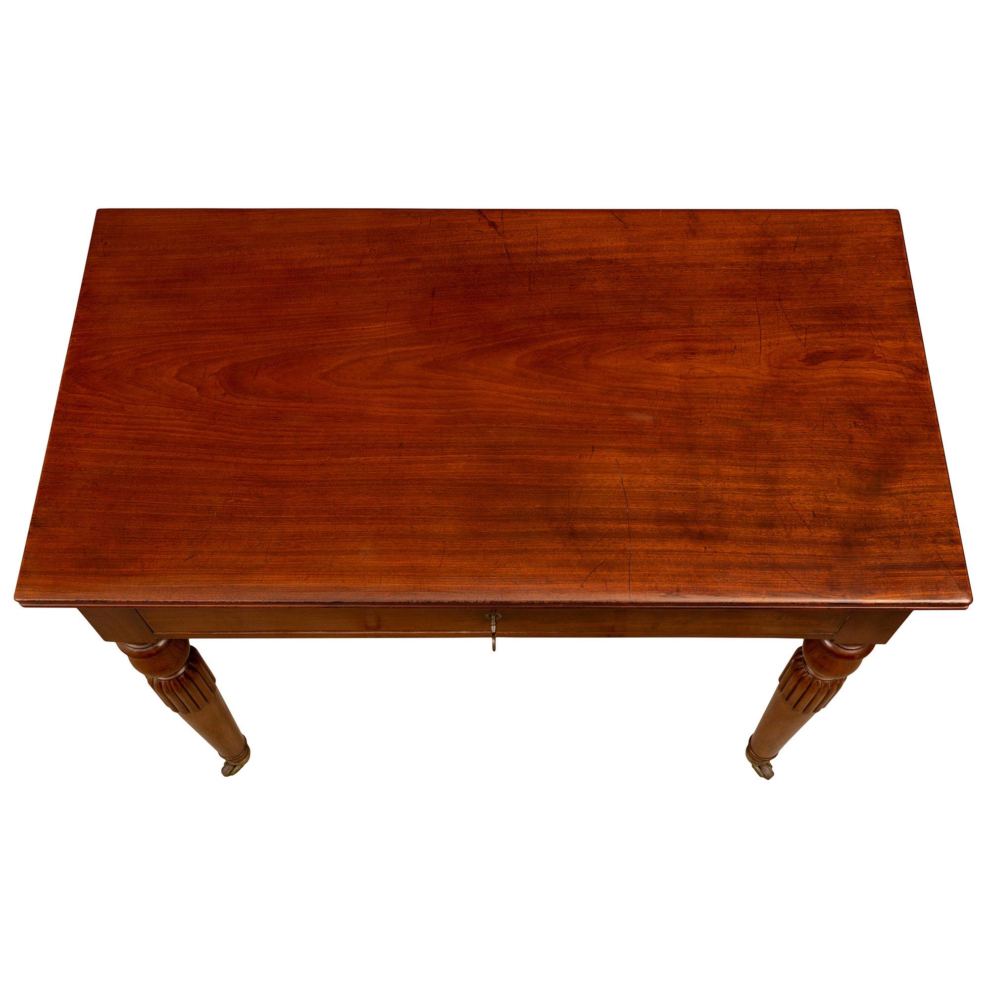 A beautiful and most unique French early 19th century Louis Philippe period Mahogany side table/desk. The desk is raised by elegant tapered turned circular legs with their original casters and an exceptional reeded and mottled design below the