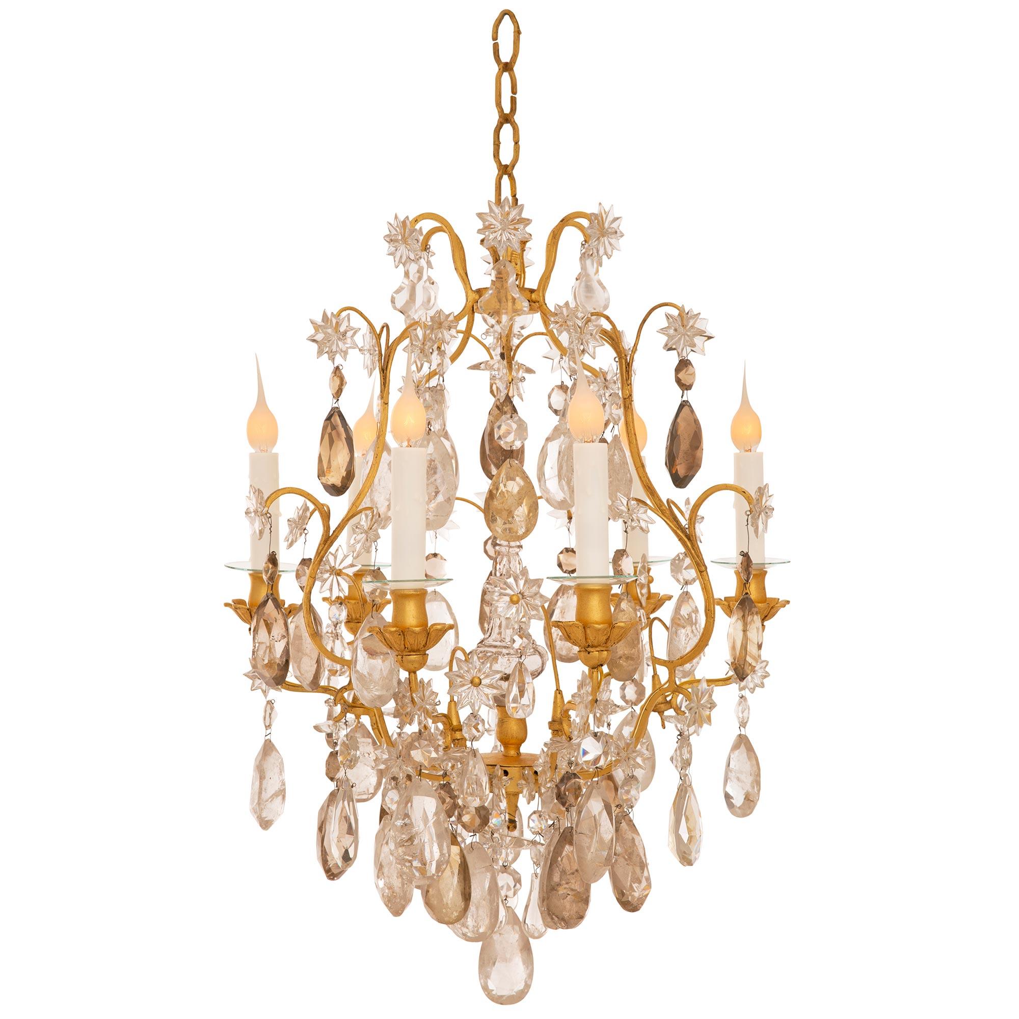 A stunning and very charming French early 19th century Louis XV st. rock crystal and gilt metal chandelier. The six arm chandelier is centered by a unique and most decorative cut oblong shaped rock crystal pendant centered by exceptional teardrop