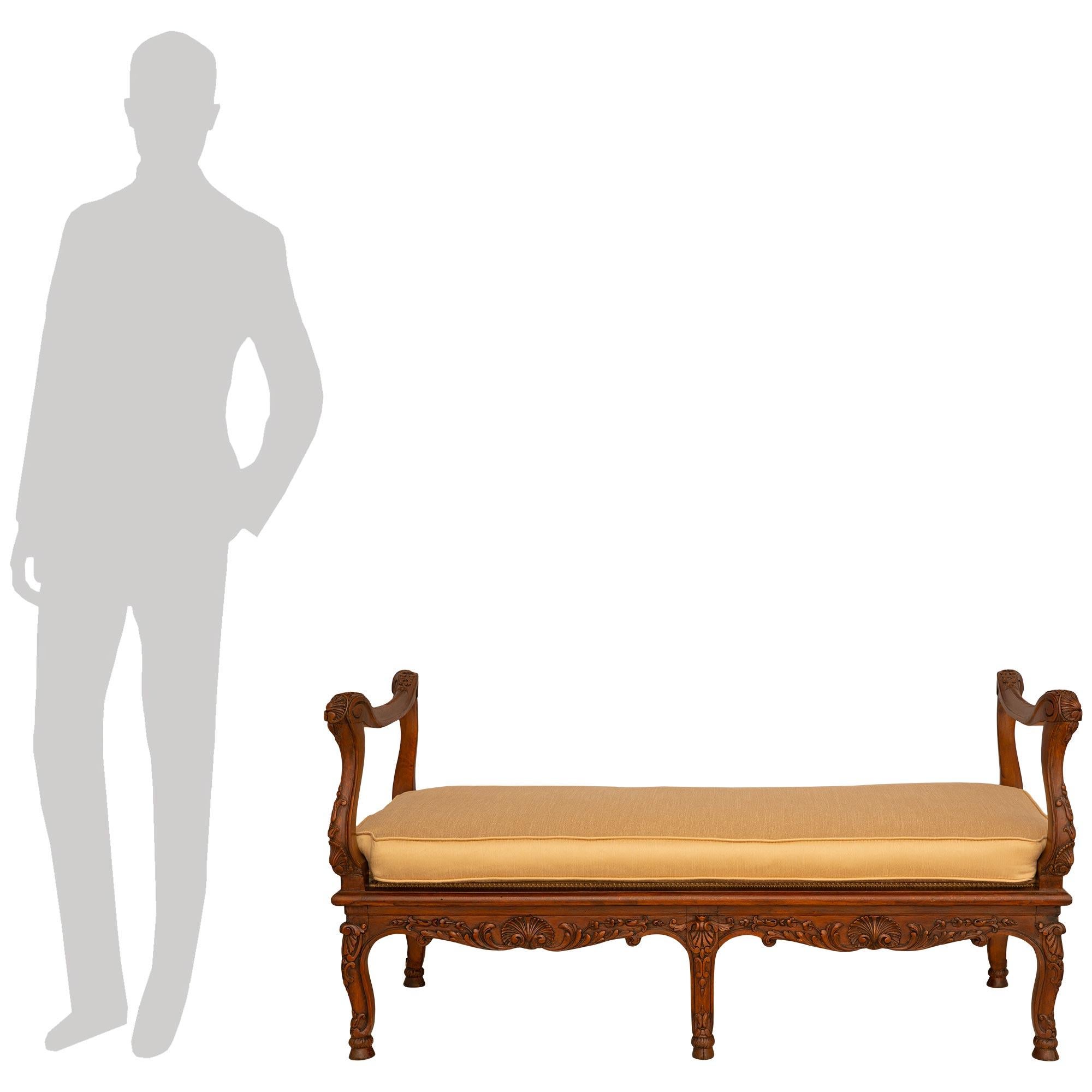 Un beau banc en noyer de grande qualité, de style Louis XV, du début du 19e siècle. Ce banc attrayant est surélevé par six éléments décorés de feuillages.  pieds cabrioles reposant sur des pieds sabots. Les capuchons de chaque pied, en forme de