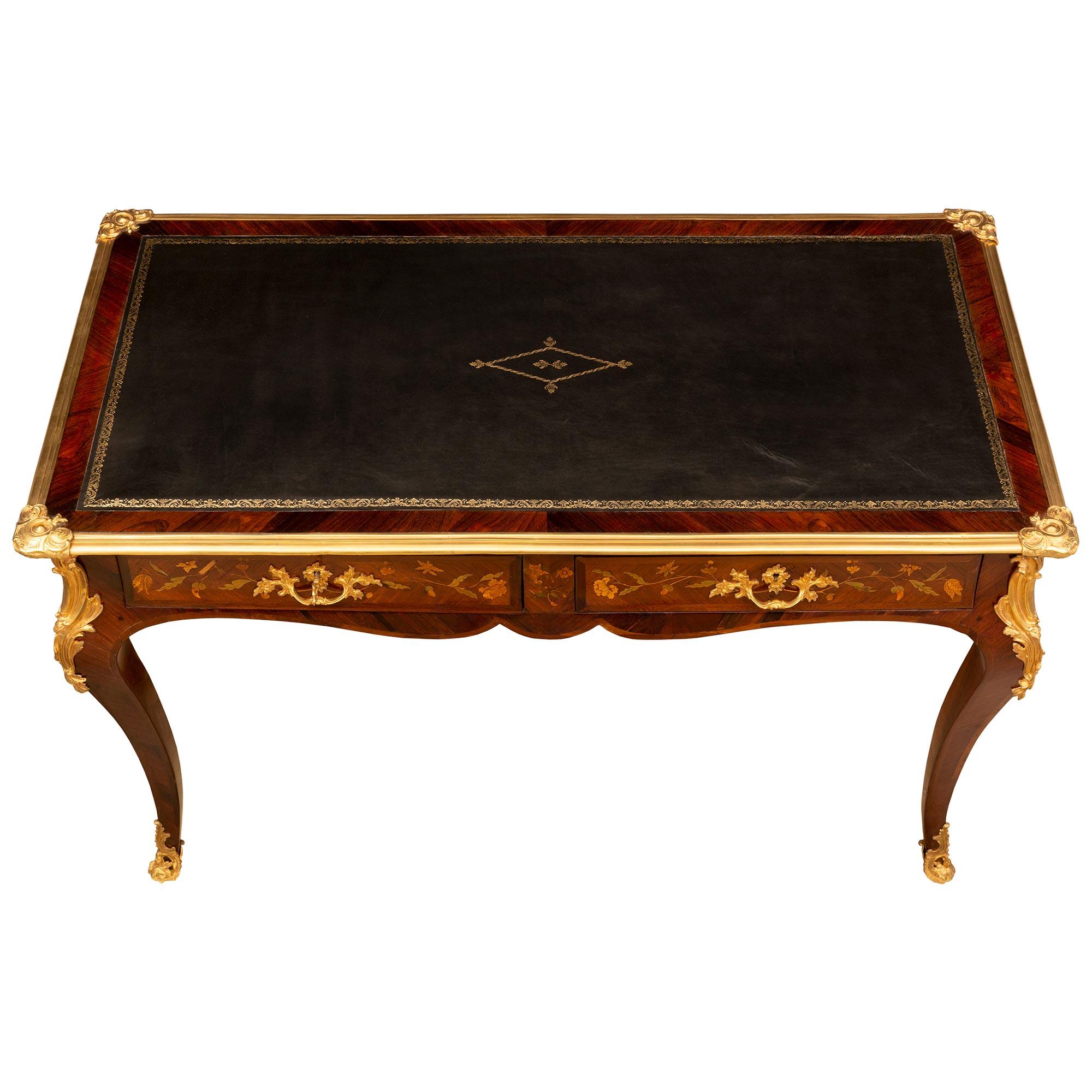 Exceptionnel et très élégant bureau plat en bois de rose, bois exotique et bronze doré de style Louis XV du début du XIXe siècle. Le bureau repose sur des pieds cabriole avec des sabots en bronze doré finement percés et ajustés, ainsi que des