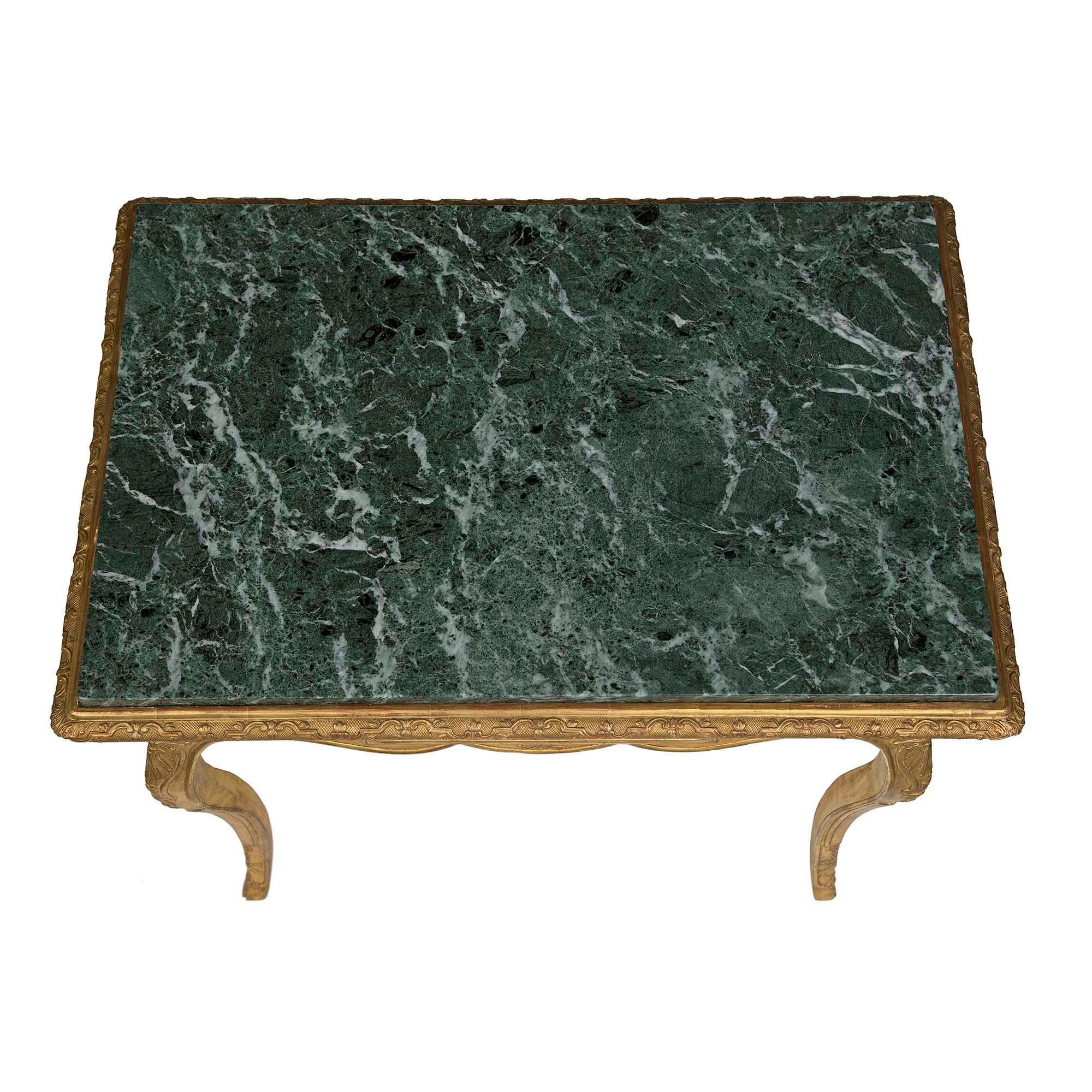 Élégante table d'appoint rectangulaire en bois doré et marbre de style Louis XV du début du XIXe siècle. La table est surélevée par des pieds cabriole avec des pieds sabots et des sculptures très décoratives avec un cabochon de coquillage à chaque