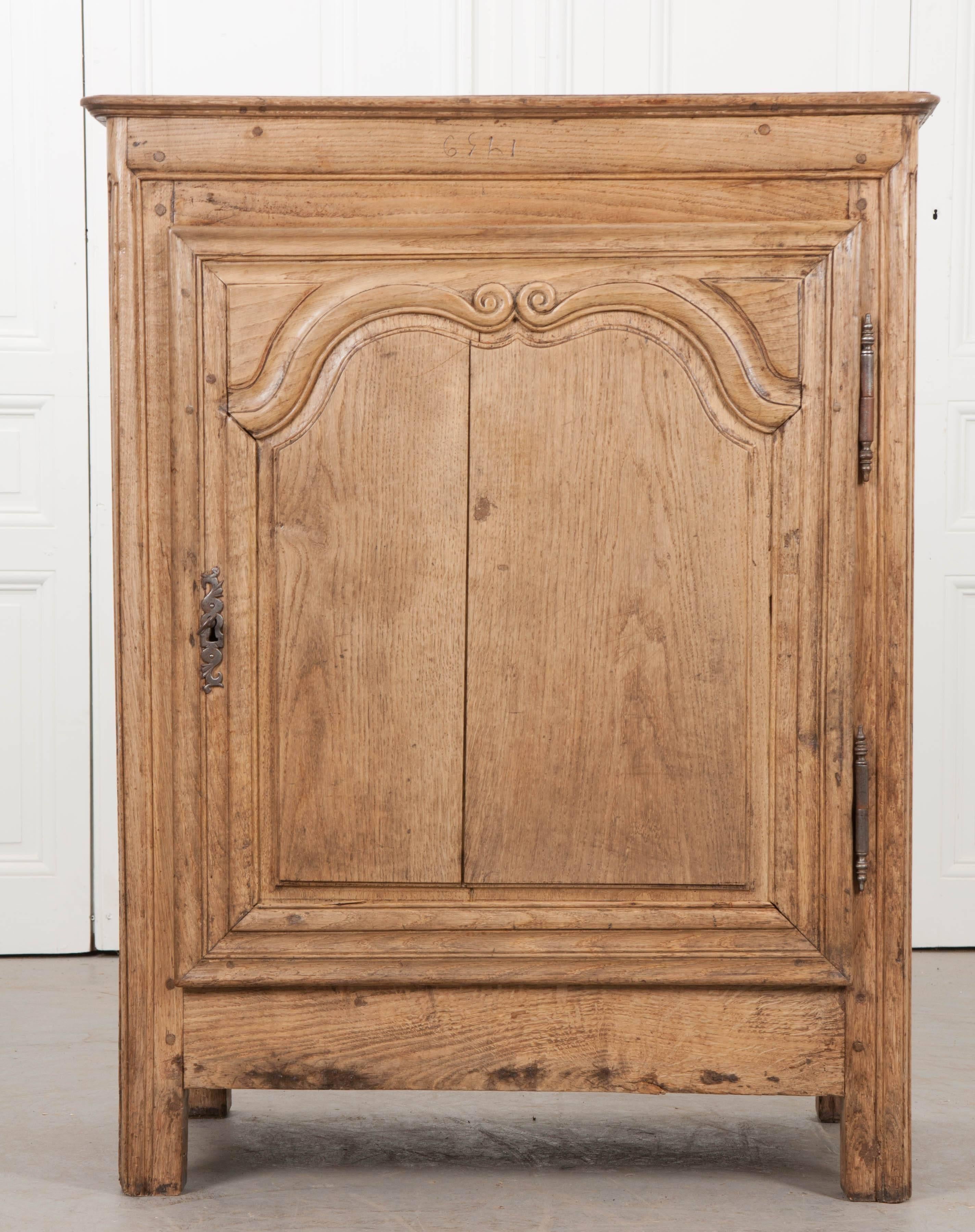 A fantastic single-door oak buffet, made in France, circa 1820. The tall cabinet was made using solid oak, which is blonde in color, and fastened together using peg joinery. The lightly toned wood exposes the beautiful grain which is sometimes less