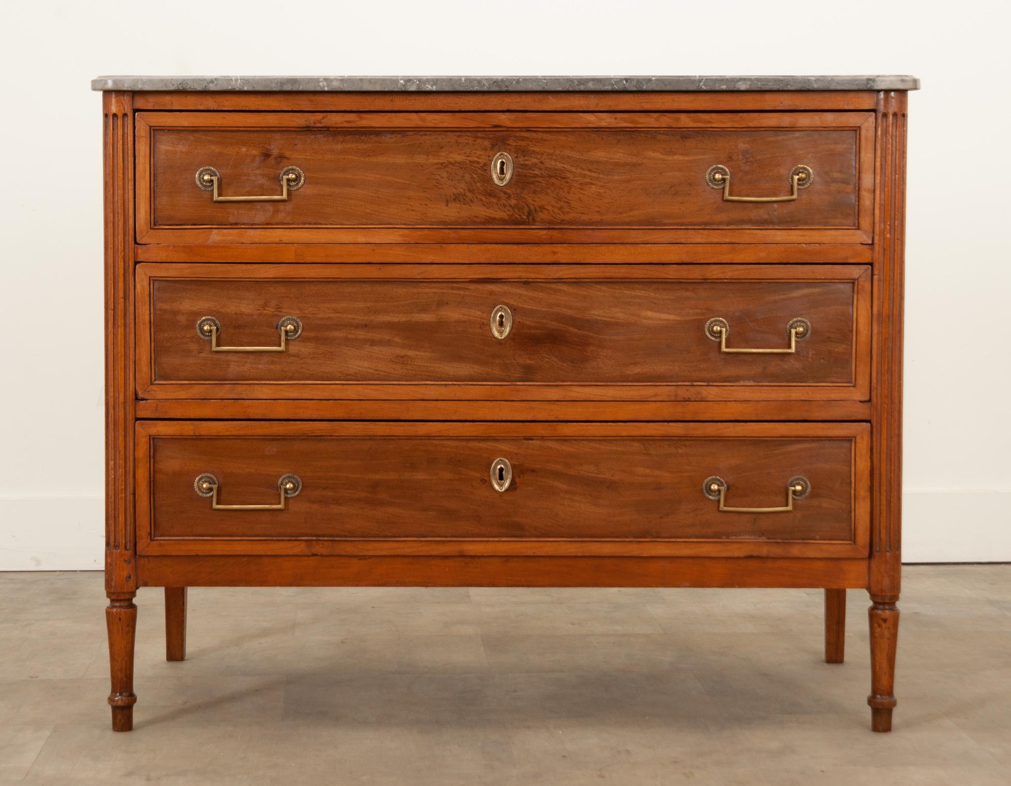 An early 19th Century Louis XVI style commode hand-crafted in France circa 1800. This stylish case piece is made of mahogany and topped with its original shaped marble top that has incredibly gorgeous patterns and charcoal and black veining