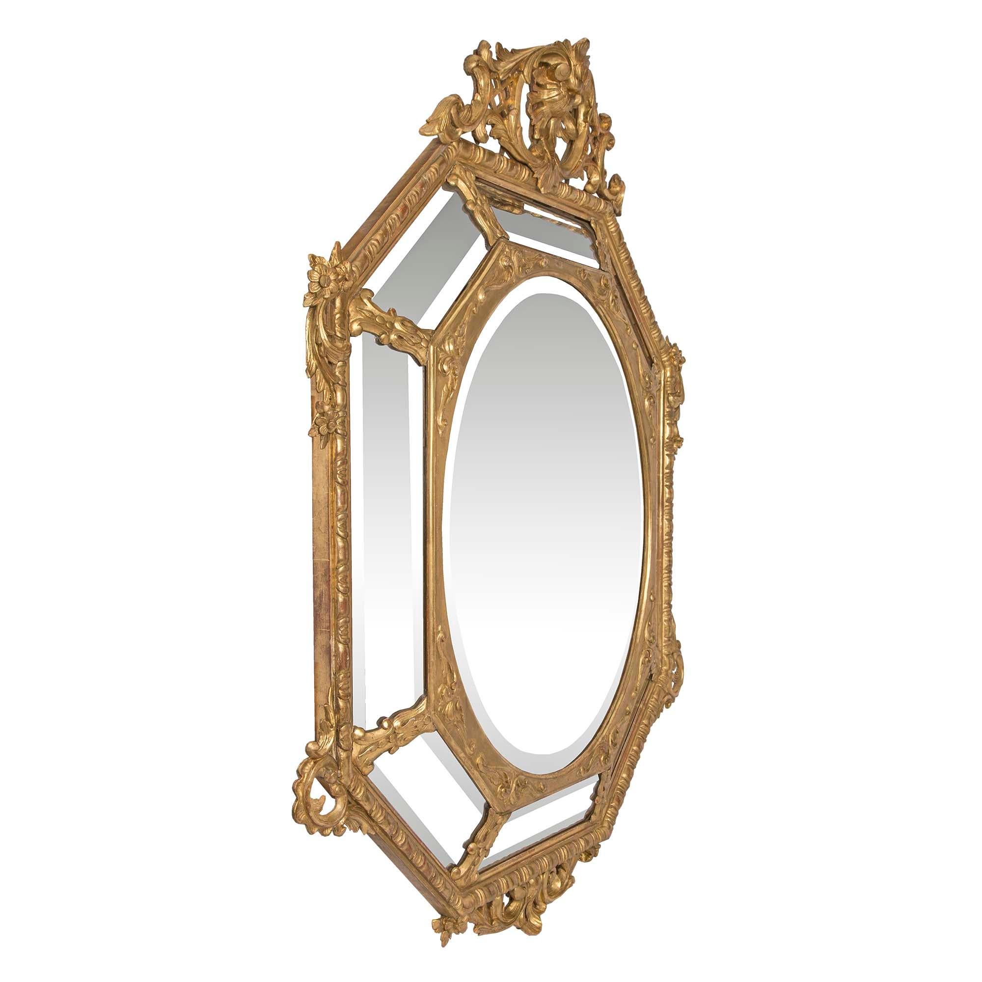 Elegant miroir octogonal en bois doré à double encadrement, de style Louis XVI, datant du début du 19e siècle. Le miroir central biseauté de forme ovale est encadré d'une bordure décorative en bois doré avec des motifs feuillagés finement sculptés.