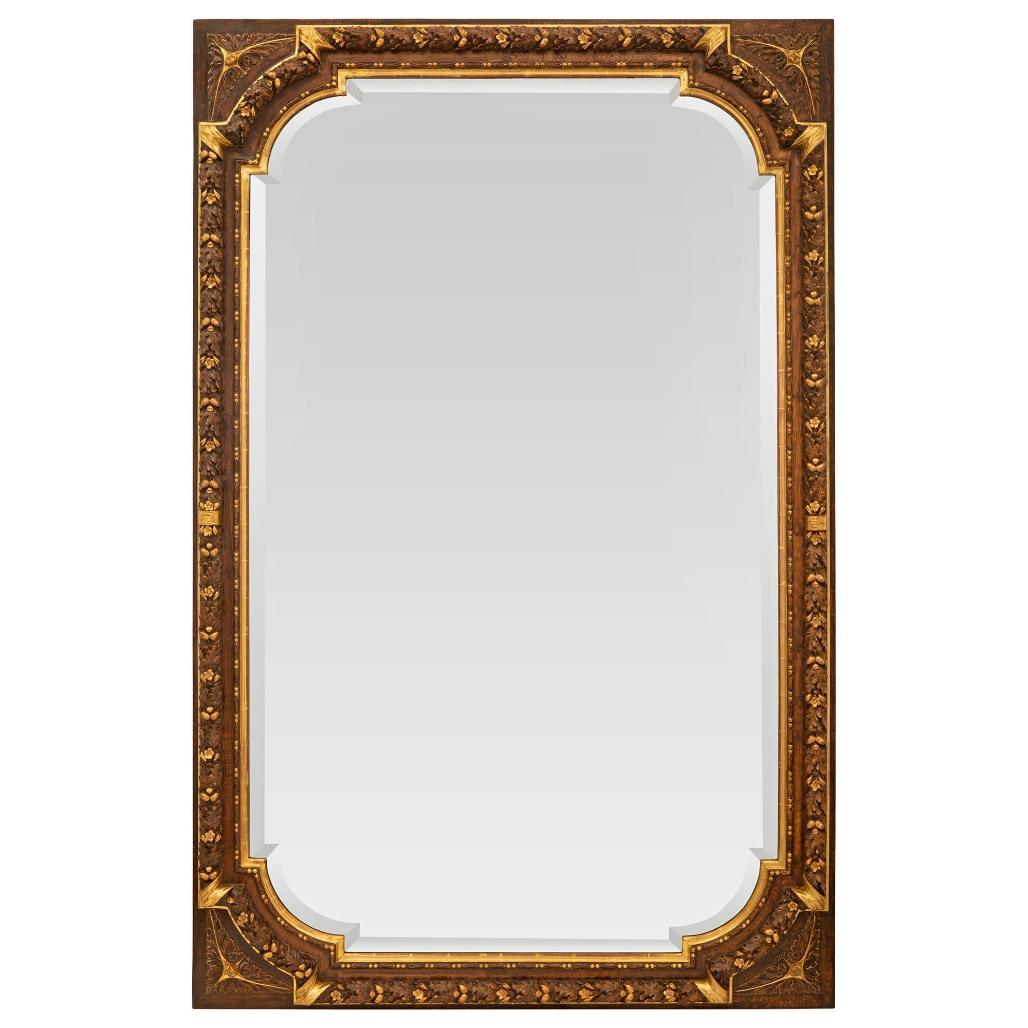 A most elegant and very unique French early 19th century Louis XVI st. patinated wood and giltwood mirror. The mirror retains its original beveled mirror plate framed within a fine wrap around mottled and beaded border. The frame displays striking