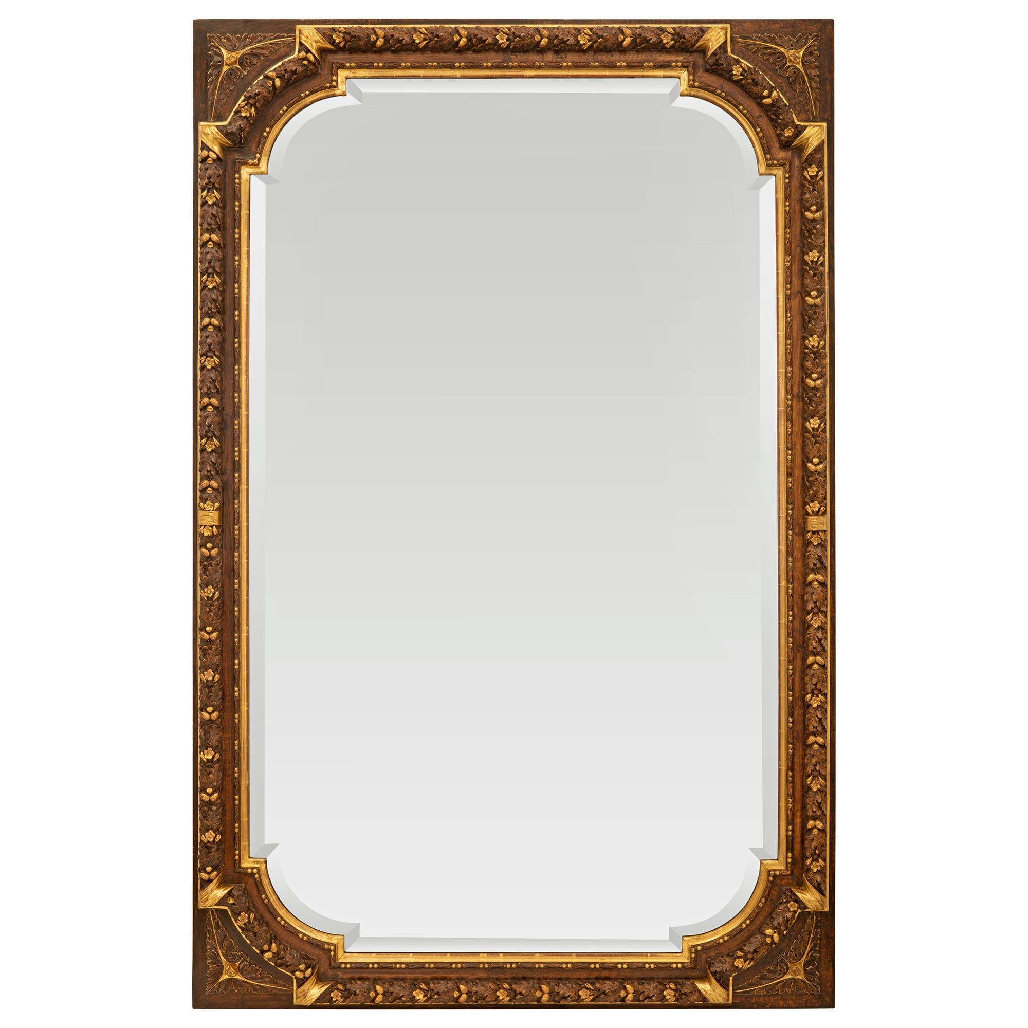 Un très élégant et très unique miroir français du début du 19ème siècle en bois patiné et doré de style Louis XVI. Le miroir conserve sa plaque biseautée d'origine, encadrée d'une fine bordure marbrée et perlée. Le cadre présente une bande de