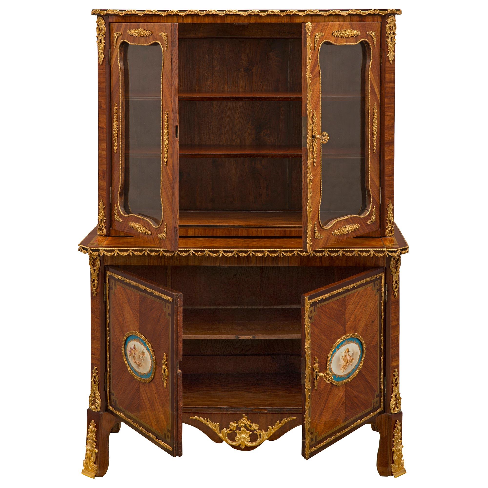 An elegant and high quality French early 19th century Louis XVI st. Kingwood, Tulipwood, Charmwood, ormolu and Sèvres porcelain cabinet vitrine. The four door vitrine is raised by fine block feet with exceptional foliate ormolu sabots flanking the