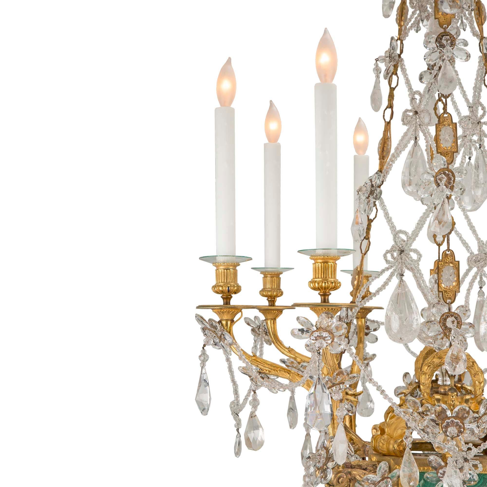A stunning French early 19th century Louis XVI st. ormolu, rock crystal malachite eight arm chandelier. The chandelier is centered by a striking tear drop shaped rock crystal pendant below a richly chased ormolu acorn finial and fluted bottom base,