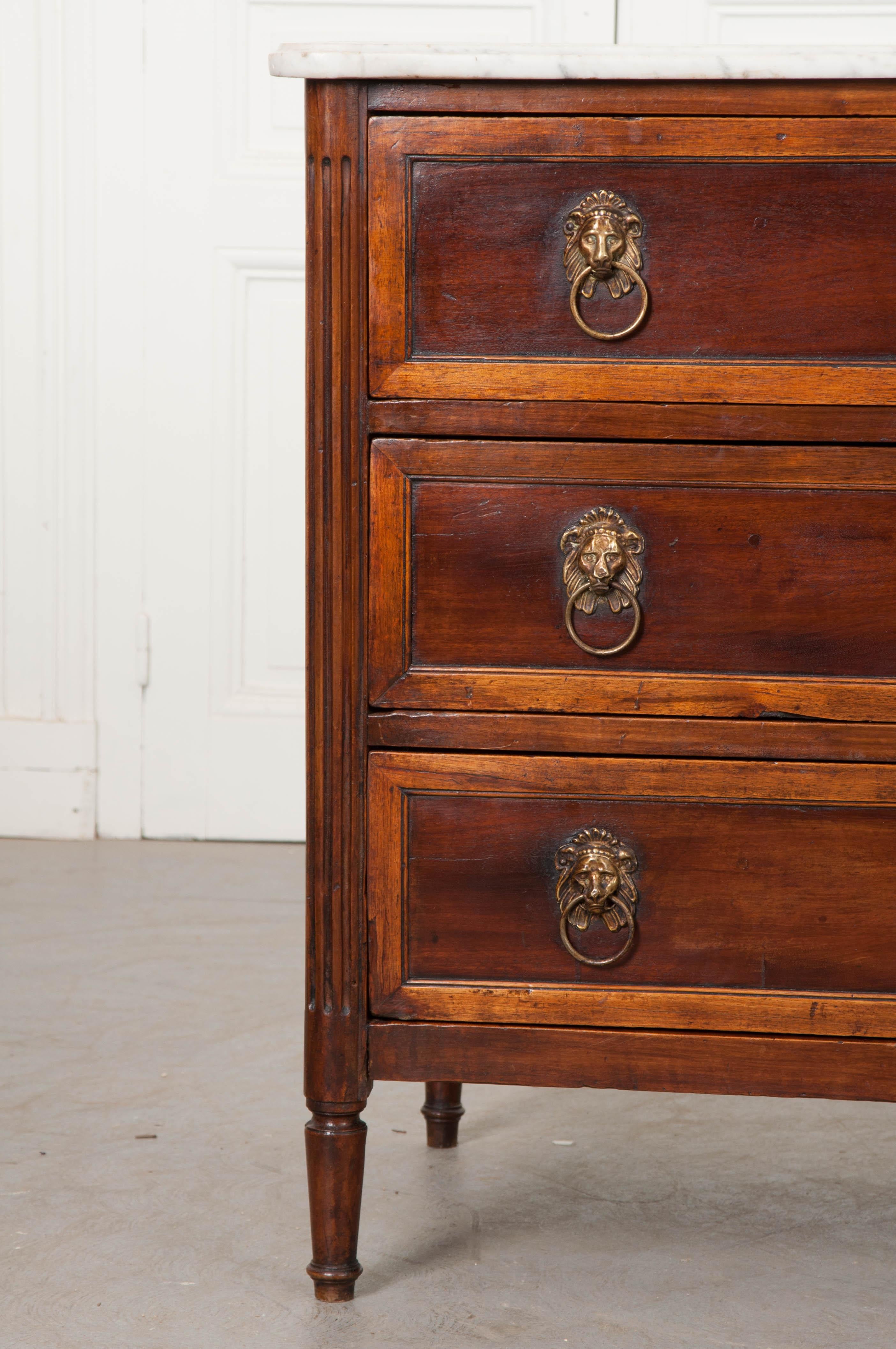 A strapping three-drawer commode, made of mahogany and walnut, from the early part of the 19th century, France. Done in the Louis XVI style, the case piece is topped in its original antique marble. The marble is in good antique condition, with wear