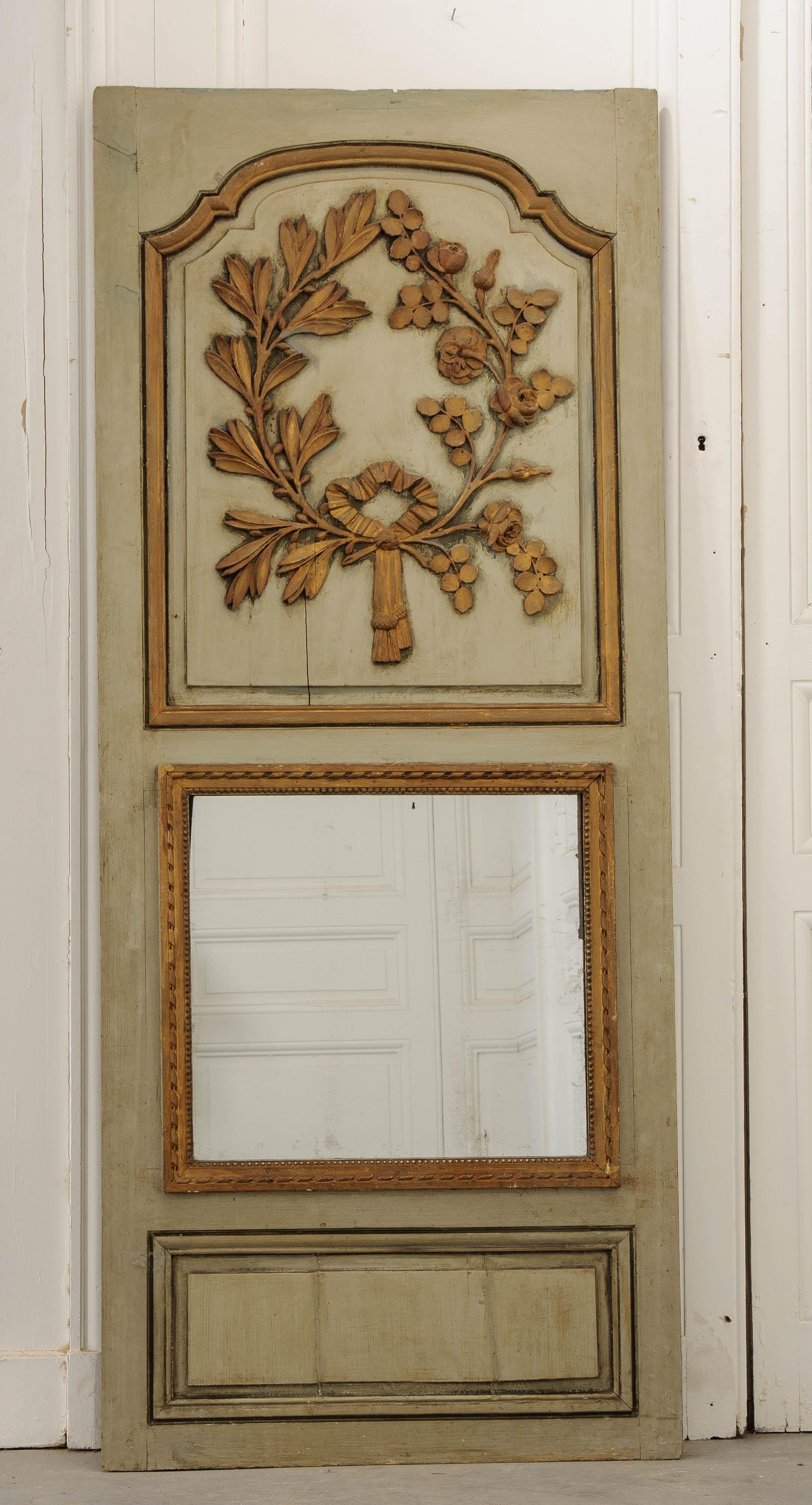 An exceptional carved and painted Trumeau mirror, circa 1800, France. The antique mirror features a large carved and gilt wreath that is situated in the larger shaped panel above the glass. It consists of carved and blossoming roses on one side,