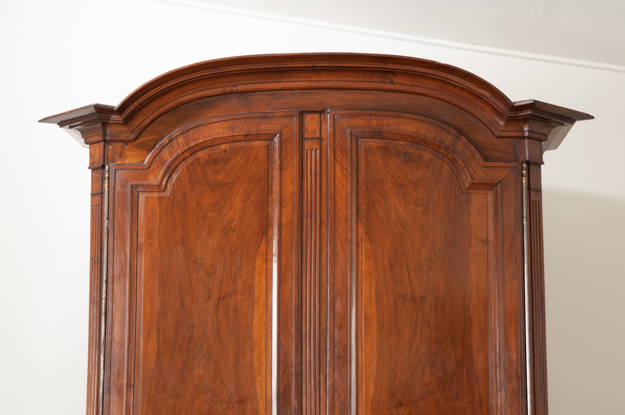 A spectacular solid walnut armoire, made in France towards the beginning of the 19th Century. The large case antique is crowned with a Chapeau de la Champ style bonnet - named after the hats worn by French military field officers of the time. The