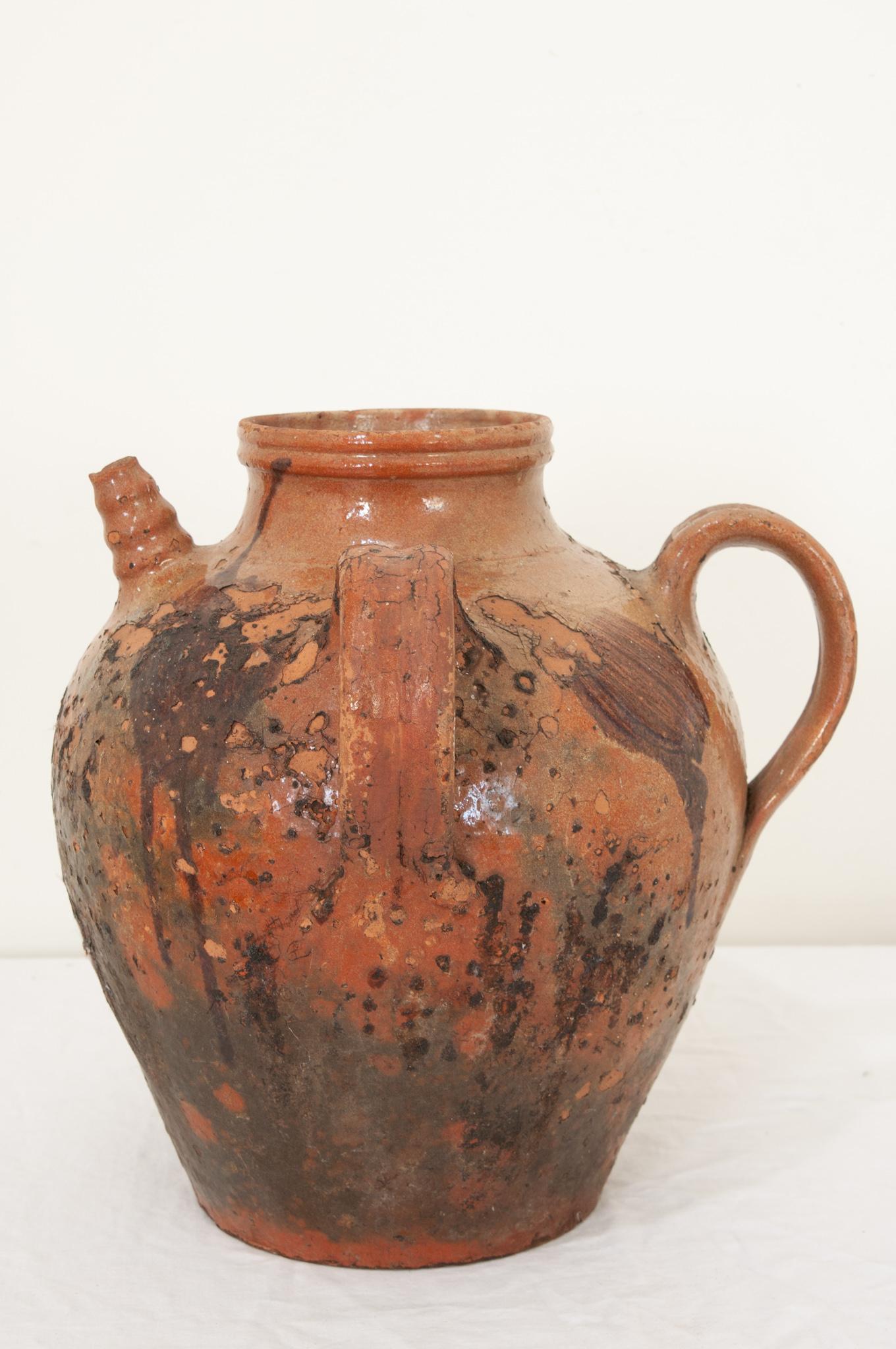 A French terracotta olive oil jar from the early 19th century, with wonderful glazes of vibrant orange and energetic black splashes that surround the entire piece. Hand-crafted in France circa 1800 this terracotta oil jar has a top circular opening
