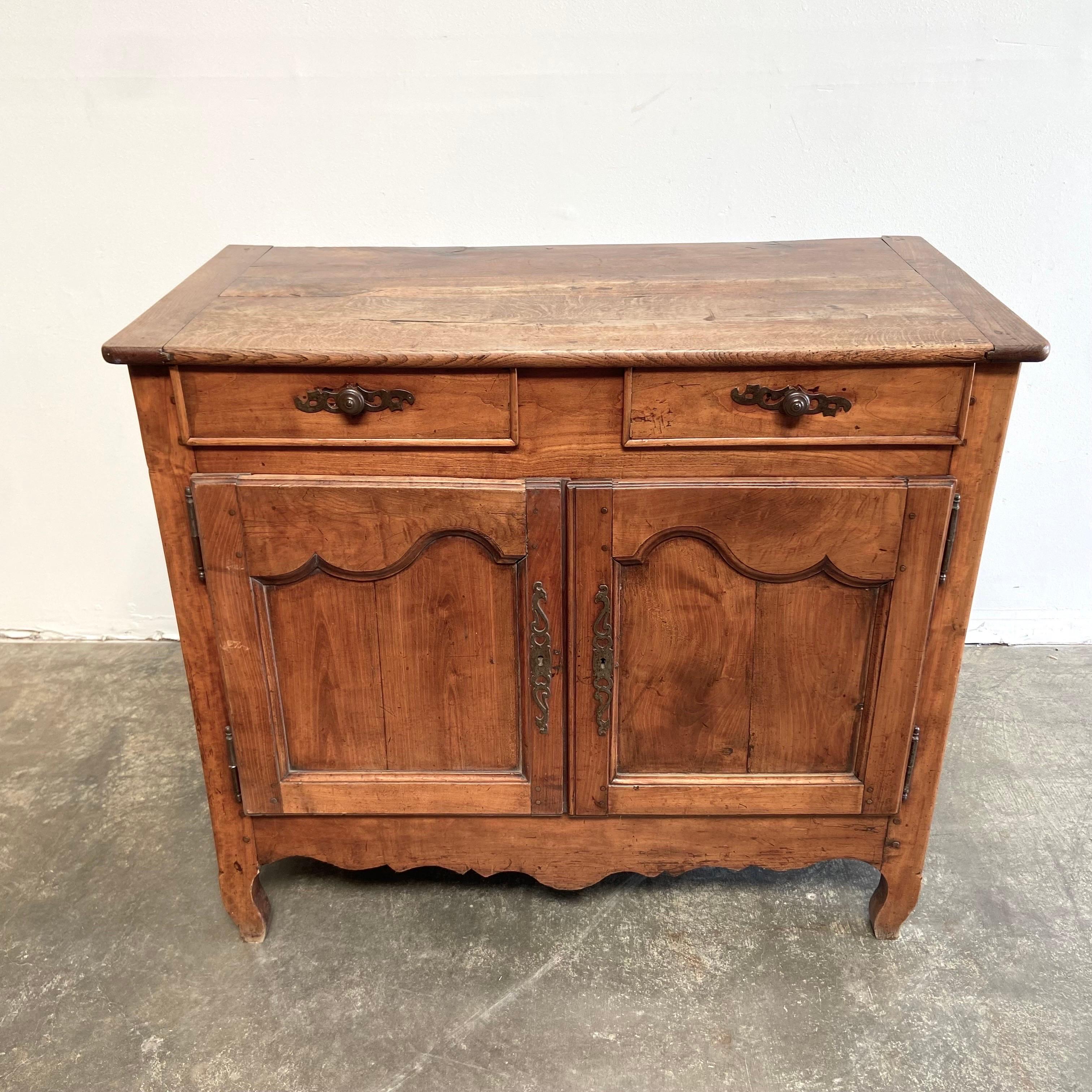 French walnut cabinet 44”w x 22”d x 29”h
A French Transition style walnut buffet from the early 19th century, with two drawers over two doors, carved stars and scalloped apron. Created in France during the early years of the 19th century, this