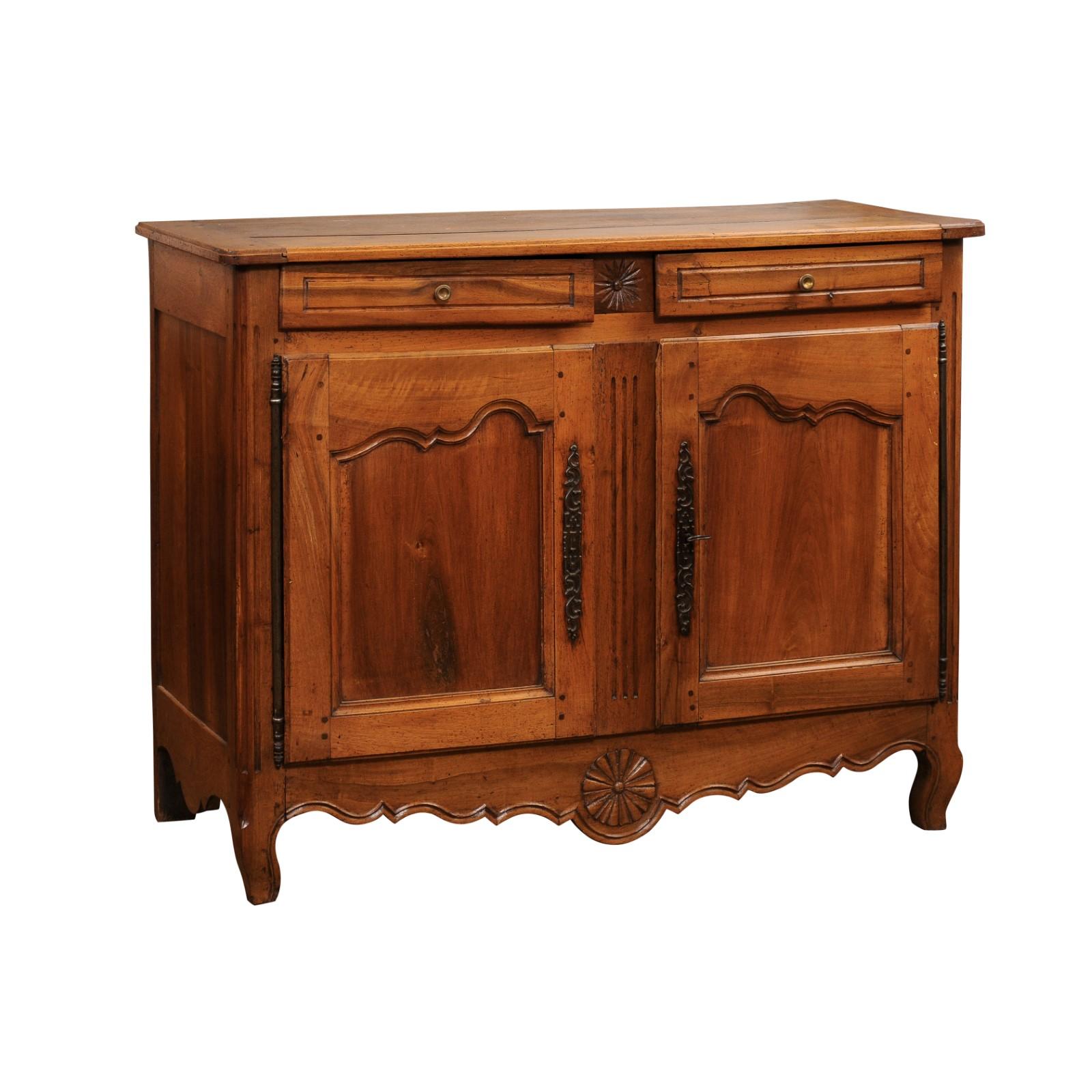 A French Transition style walnut buffet from the early 19th century, with two drawers over two doors, carved stars and scalloped apron. Created in France during the early years of the 19th century, this walnut buffet belongs to the 
