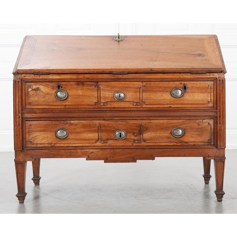 This amazing walnut desk has a slanted front that drops to reveal an interior writing surface and storage. A single key works the lock to open the top and once opened, the writing surface is lined with tooled, green leather. The interior is