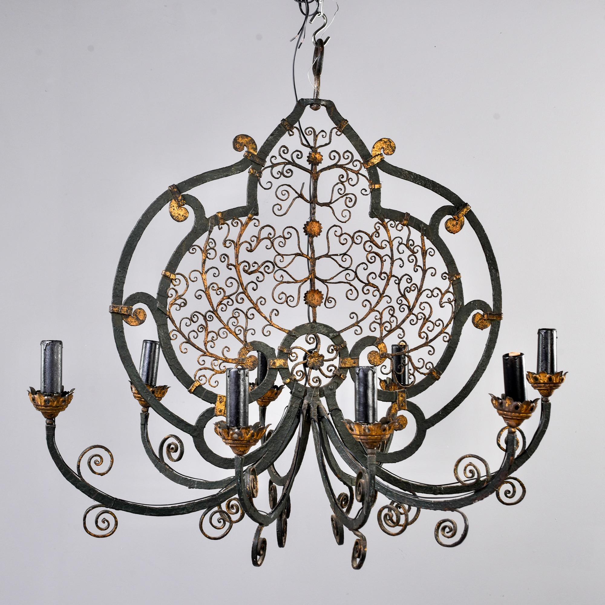 French black iron chandelier features fancy scroll work with gilded accents and eight arms with candle-style lights circa 1900s. Unknown maker. New wiring for US electrical standards. 

# of Sockets: 8
Socket size: Candelabra.