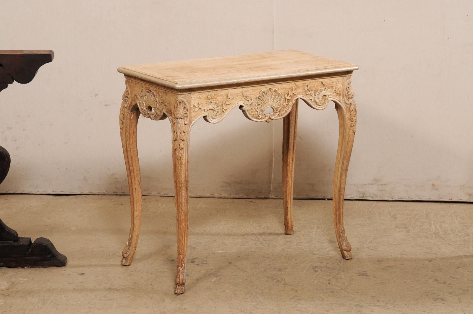 A French pair of smaller-sized carved-wood tables from the early 20th century. These antique tables from France each feature slightly overhanging rectangular-shaped tops with smoothly-rounded corners, over aprons which are elaborately hand carved in