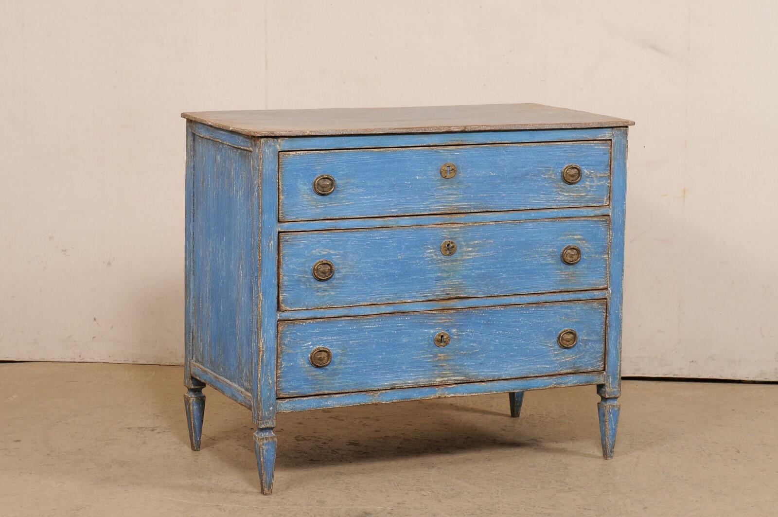 A French painted wood commode from the early 20th century. This antique chest of drawers from France has a rectangular-shaped top which slightly overhangs the case below which houses three graduated drawers, and is presented upon spaded legs. The