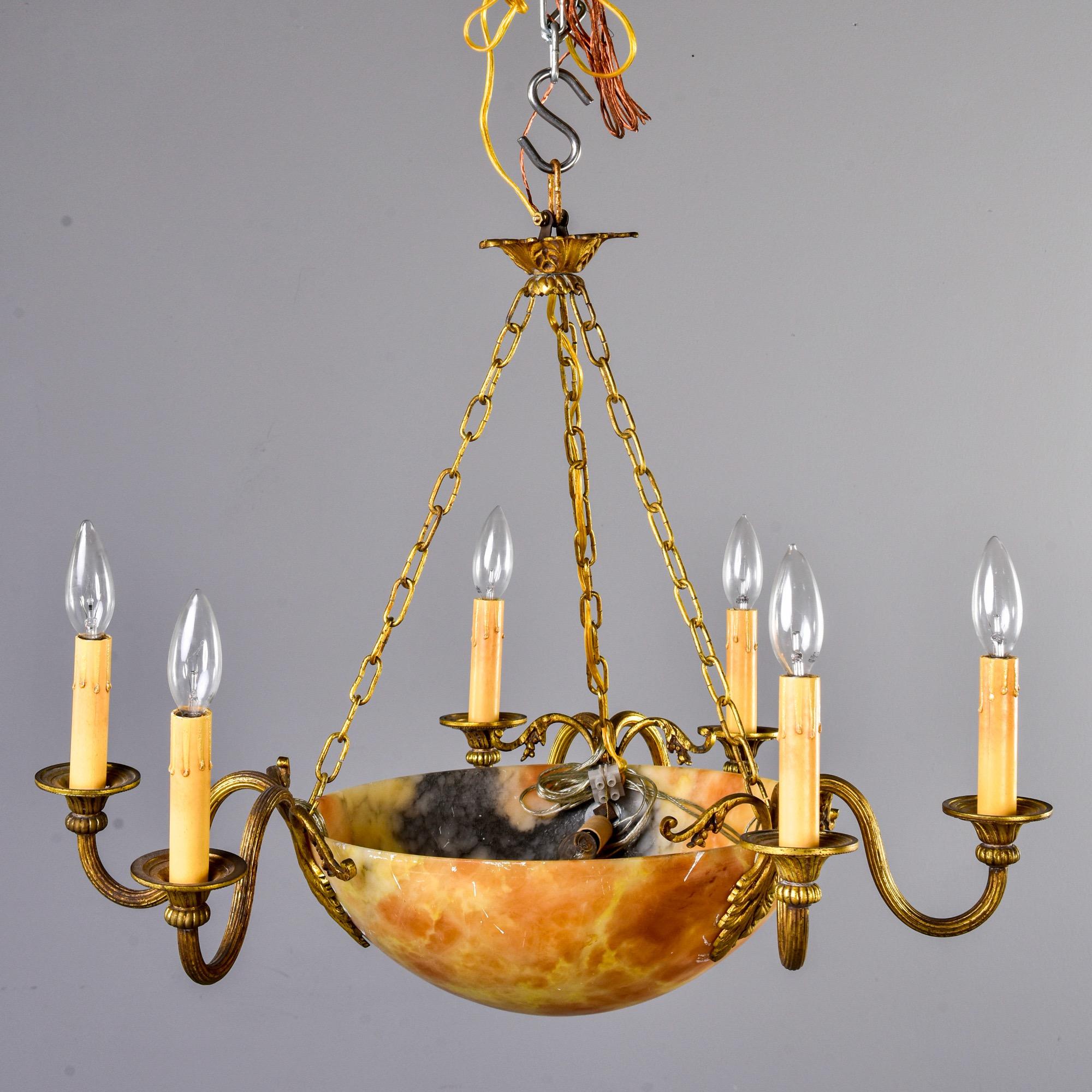 Found in France, this alabaster and brass light fixture dates from the early 20th century - circa 1910. Alabaster bowl has apricot and cream tones with some gray accents. Brass candle arms and ceiling canopy have acanthus leaf motif. Seven