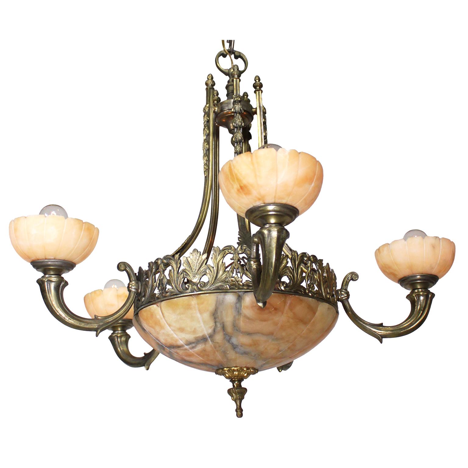 Lampadario a cinque luci in bronzo e alabastro intagliato francese dei primi del Novecento. La cornice in bronzo traforato, sospesa da cinque bretelle a volute con decorazioni ad acanto, è sormontata da cinque luci a forma di cornucopia a volute,